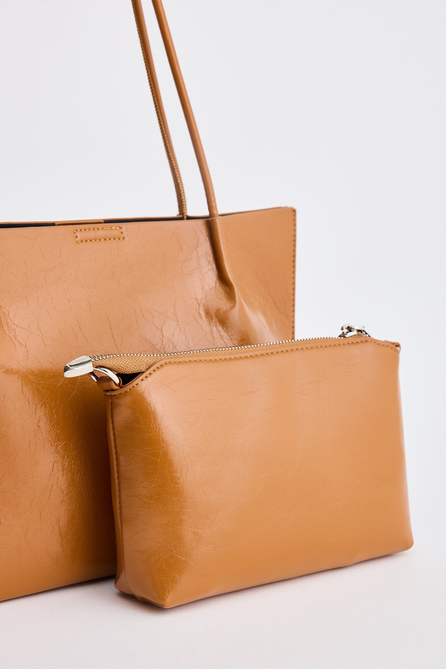 Brown leather handbag with a matching pouch on a light gray background