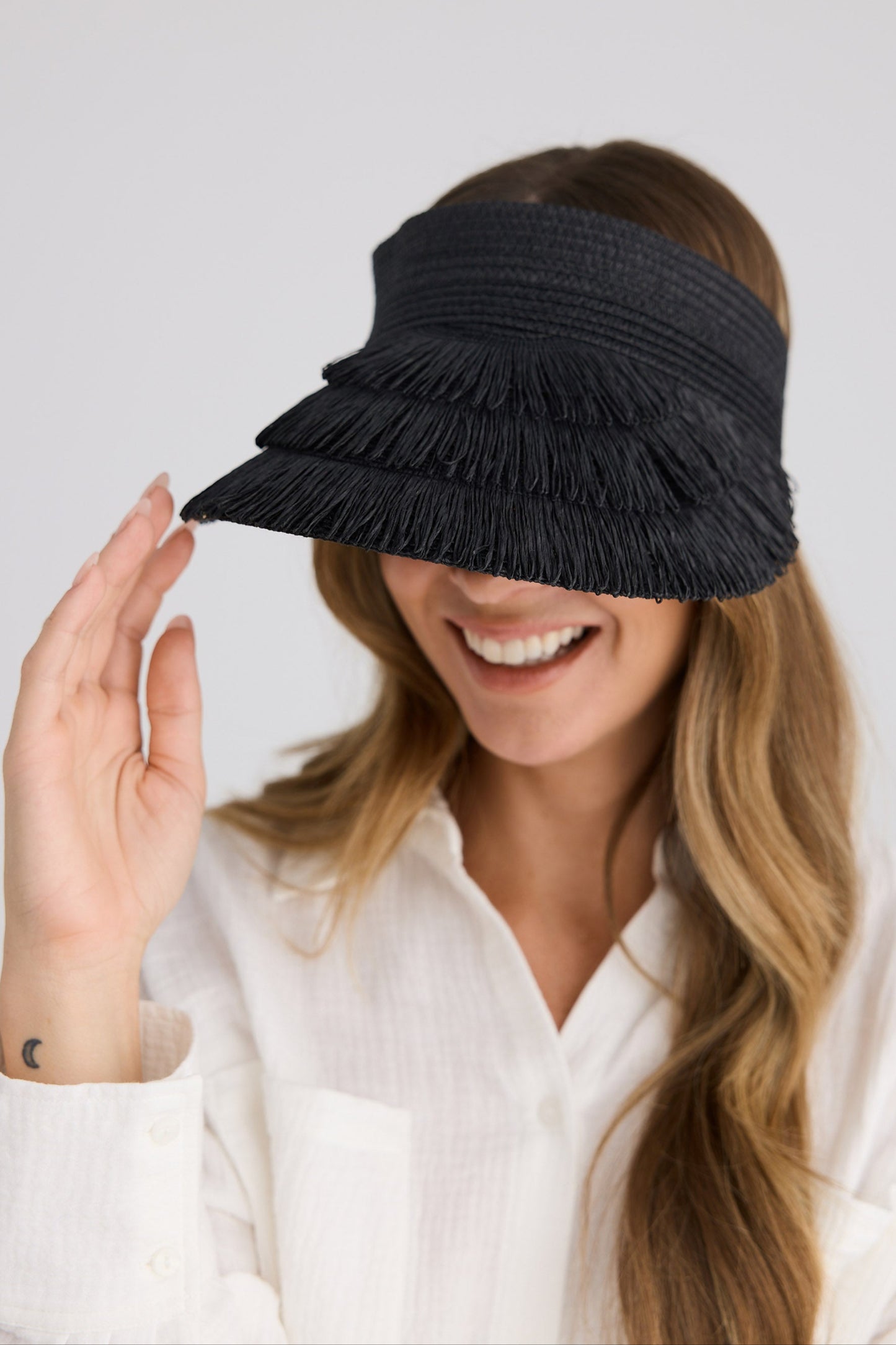 Woman wearing a black visor with ruffles on a white background