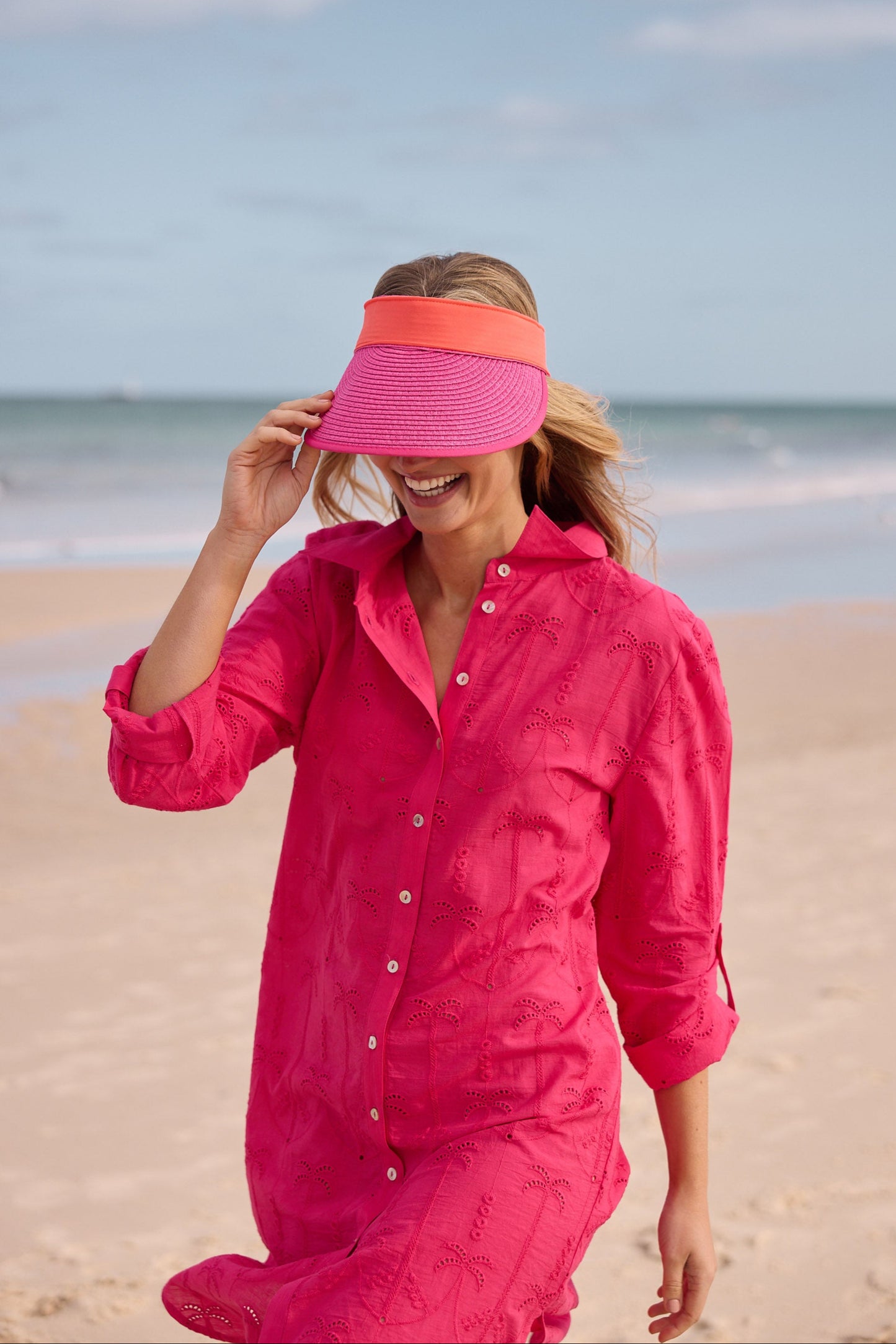 Woman in a pink outfit with a visor on a beach