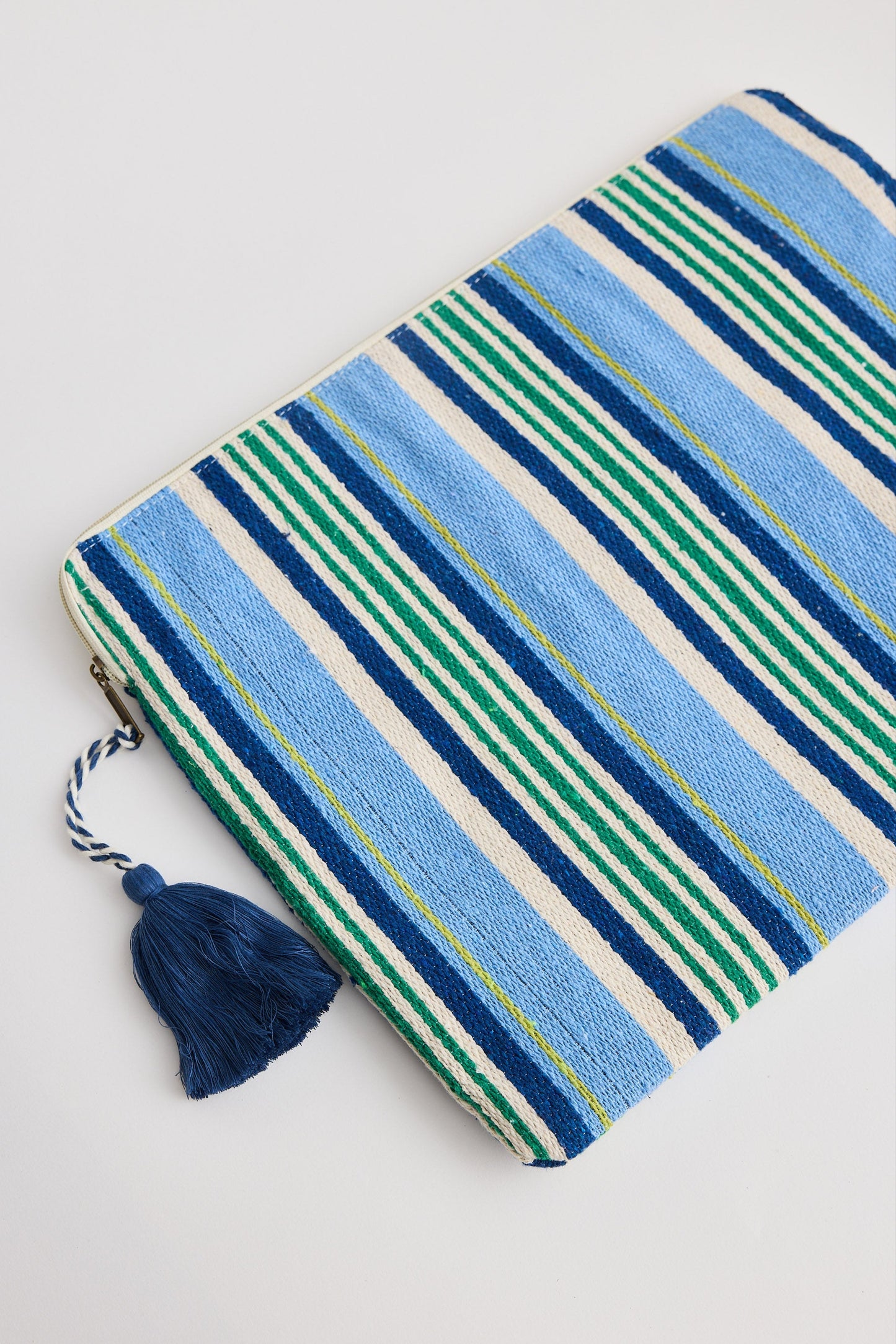 Striped clutch bag with tassel on a light gray background
