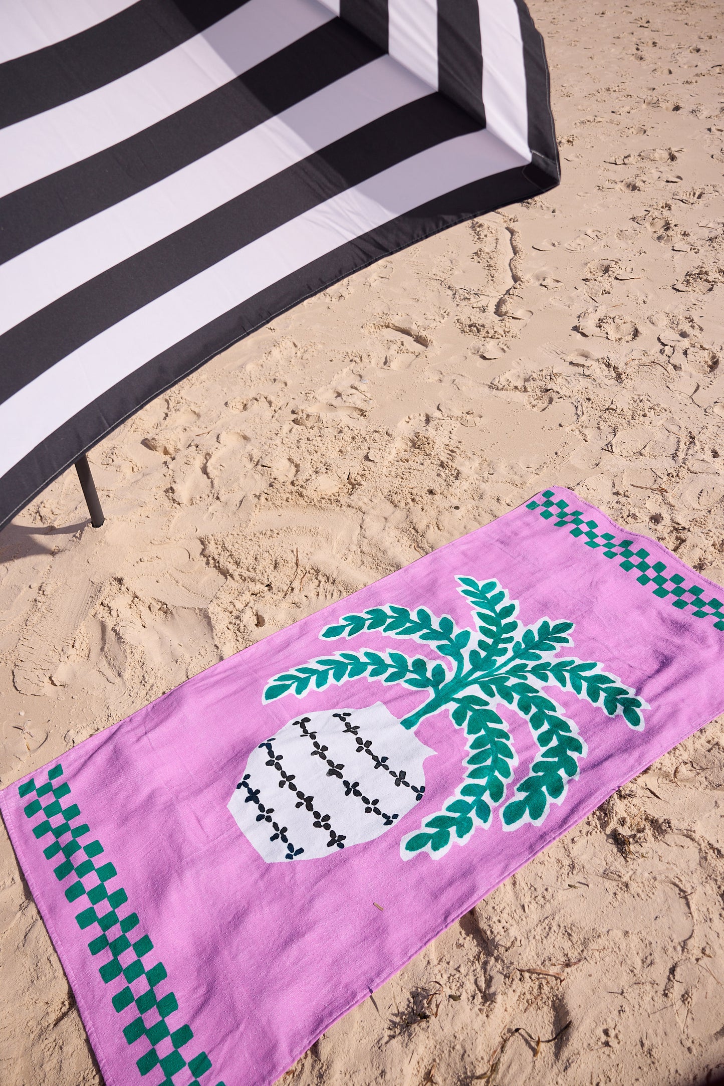 Pink beach towel with green design on sand