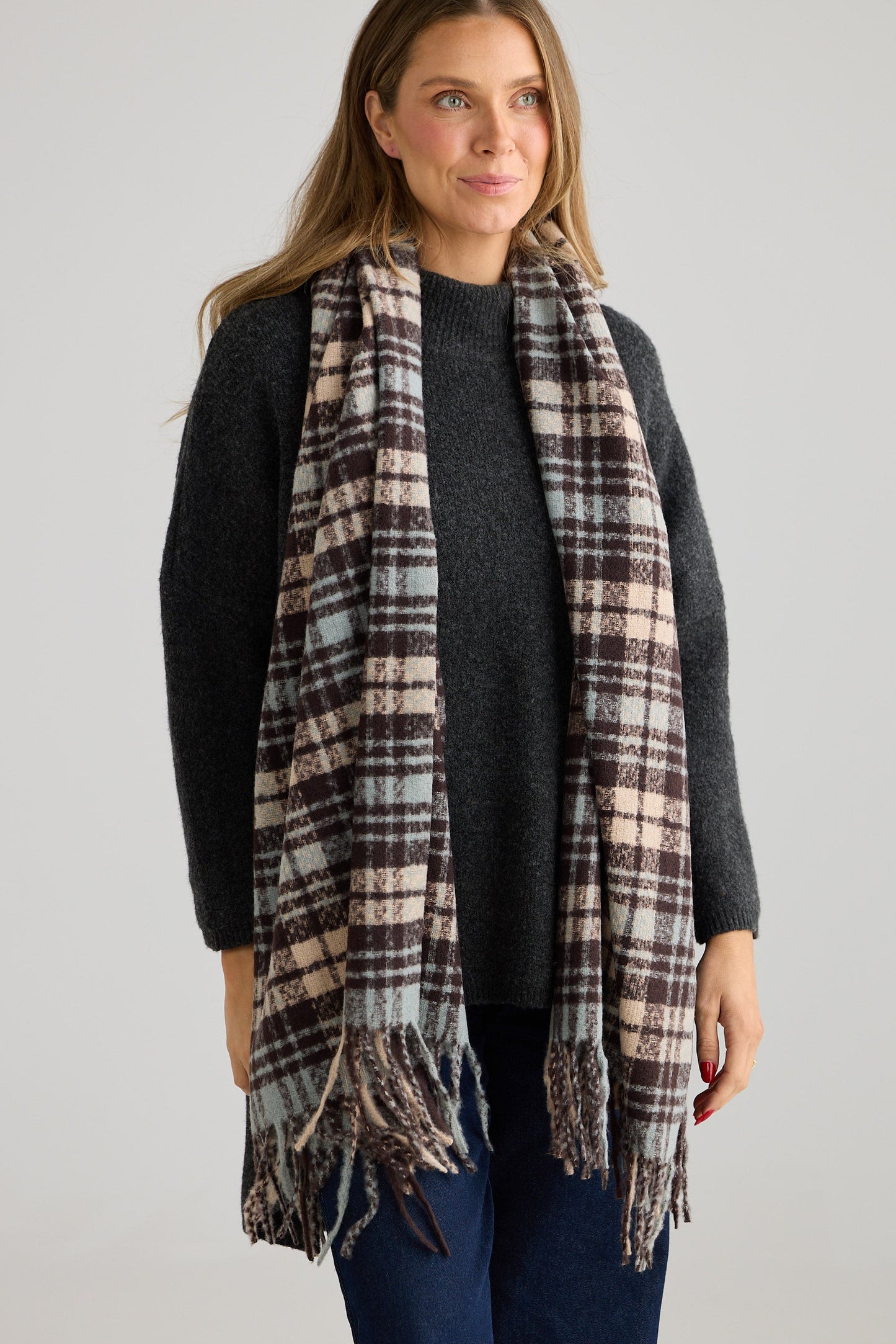 Woman wearing a plaid scarf on a plain background