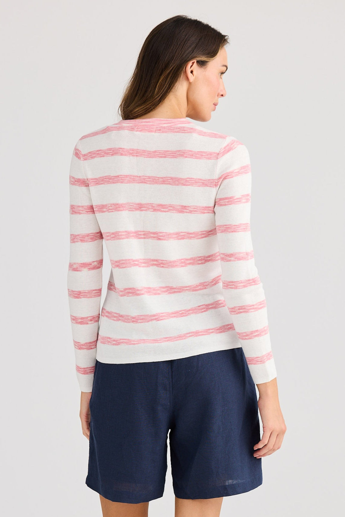 Woman wearing a striped sweater and navy shorts on a white background