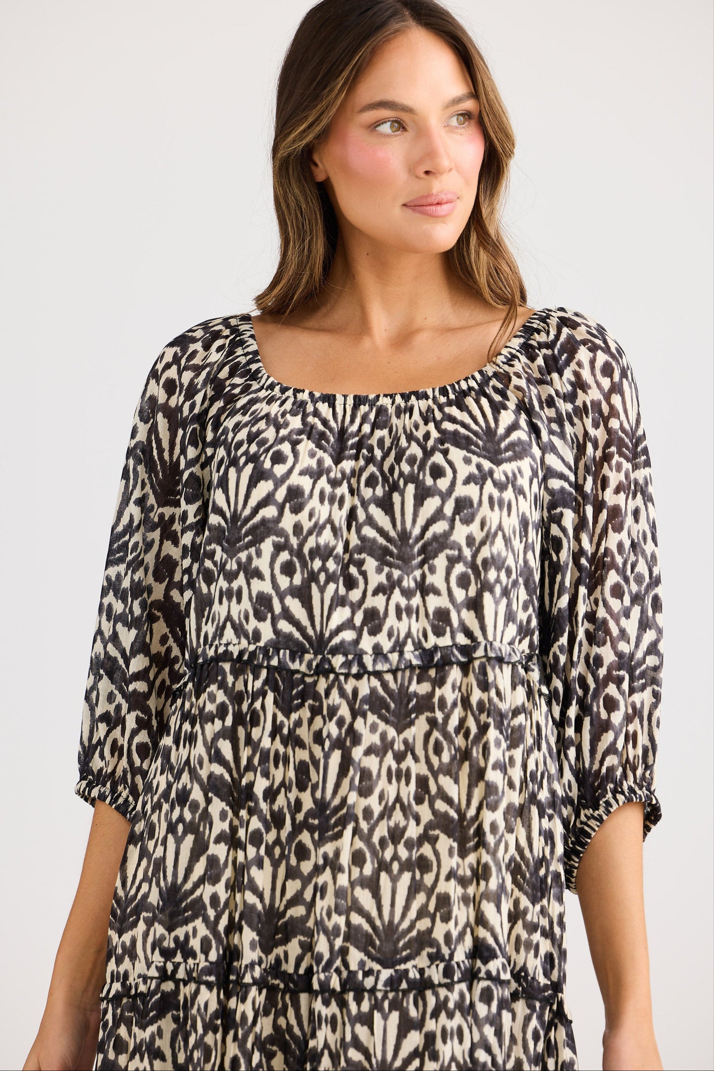 Woman wearing a patterned dress against a plain background