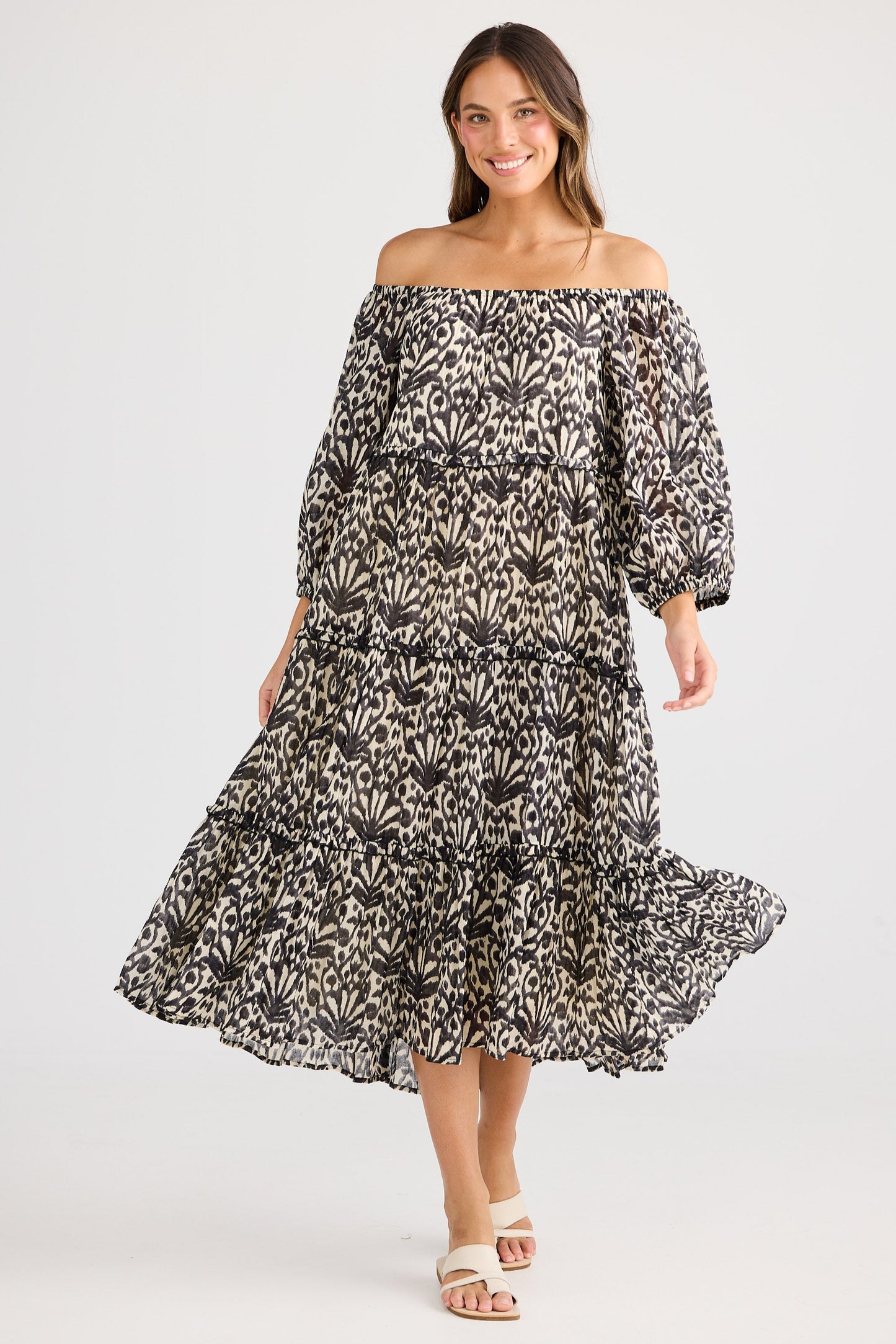 Woman wearing a black and white floral off-shoulder dress on a light gray background