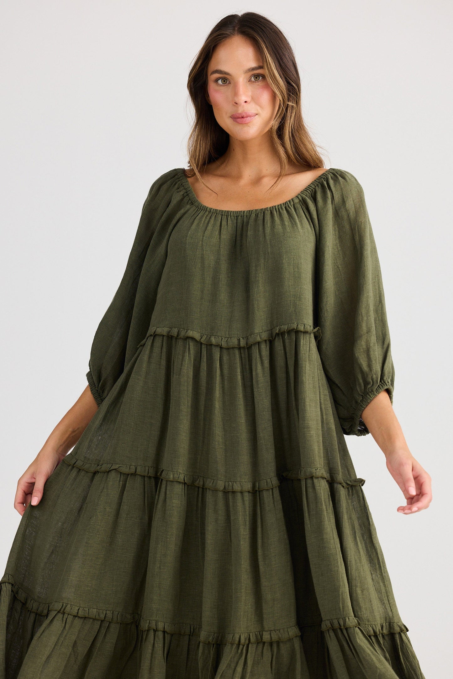 Woman wearing a green tiered dress on a white background