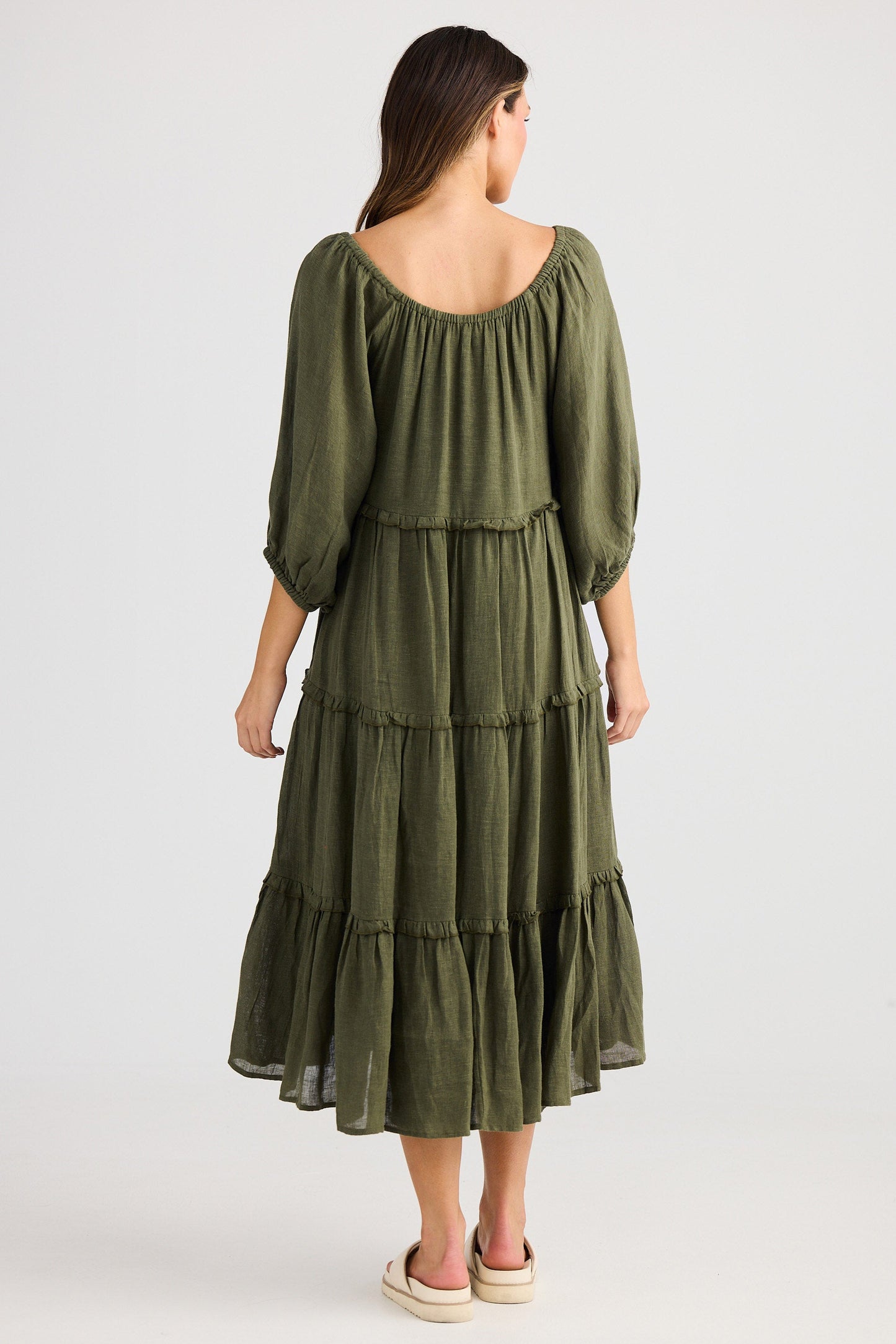 Woman wearing a green tiered dress on a white background