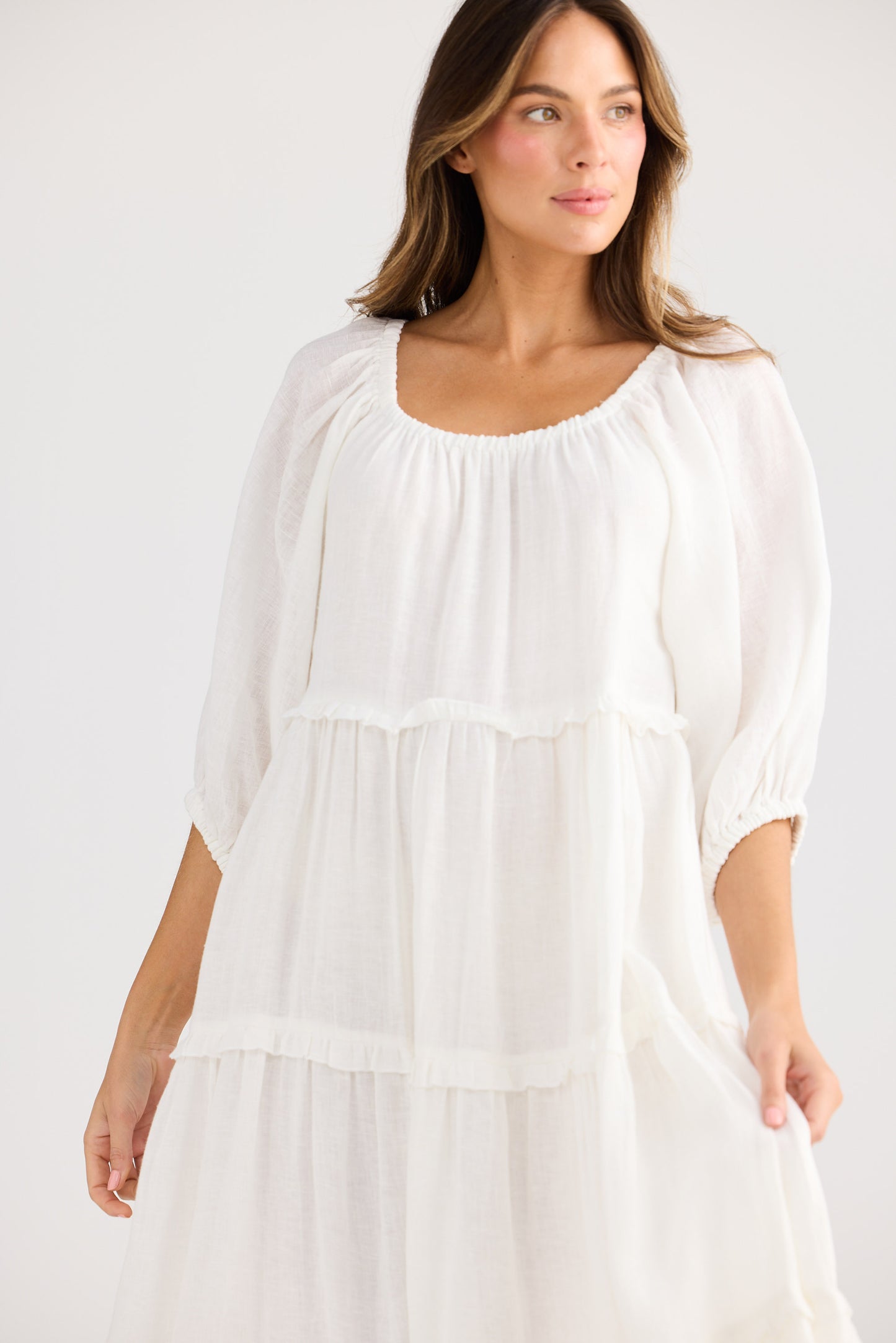 Woman wearing a white dress against a plain background