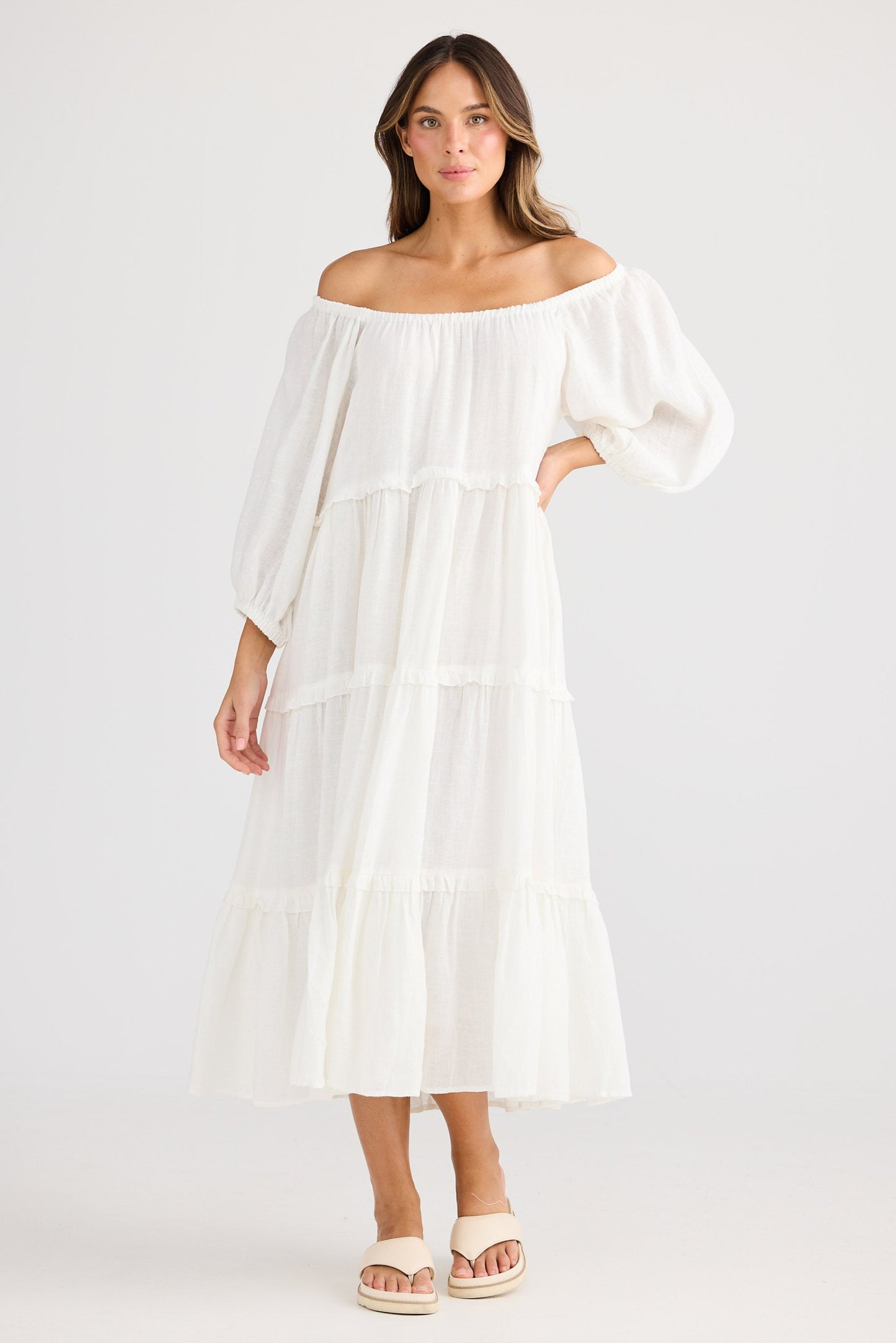 Woman wearing a white off-shoulder dress on a plain background