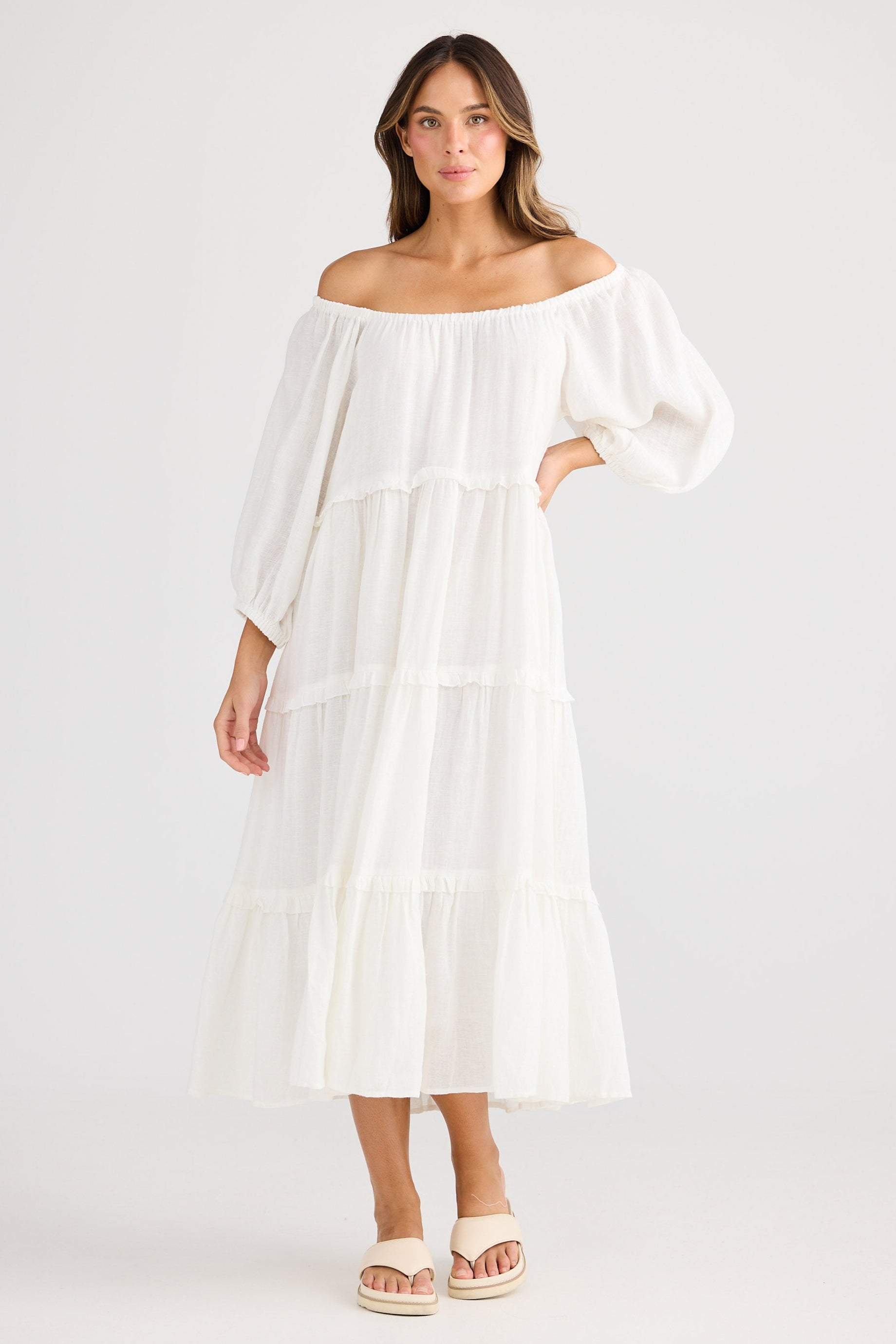 Woman wearing a white off-shoulder dress on a plain background