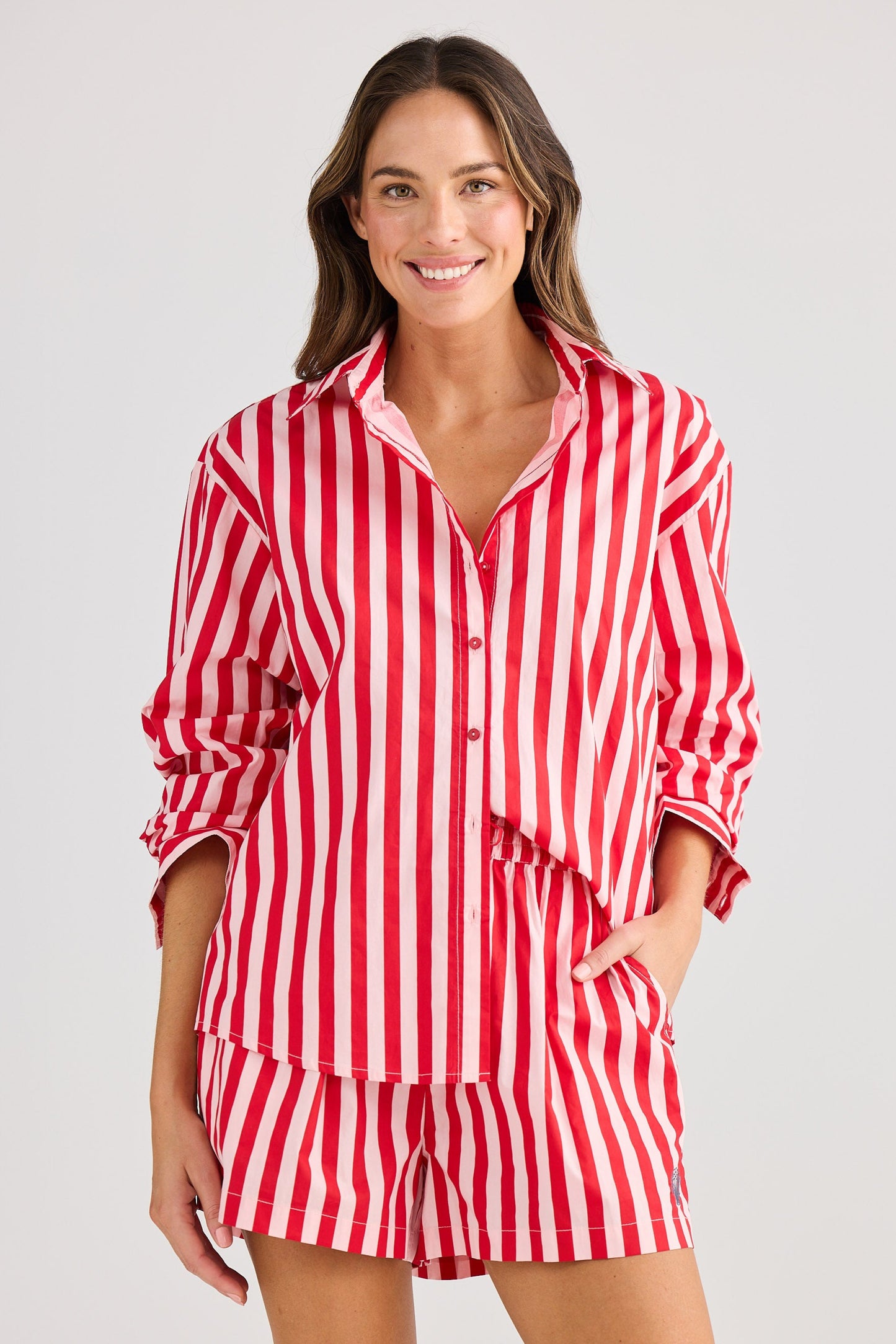 Woman wearing a red and white striped pajama set on a plain background
