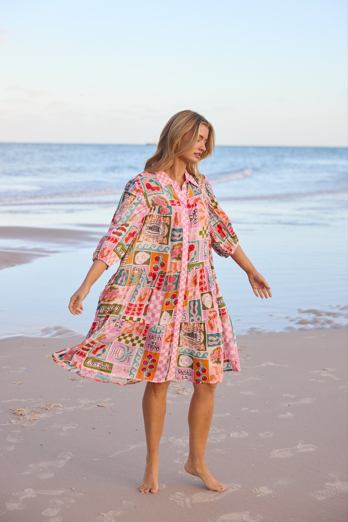 Woman in a colorful dress standing on a beach with ocean in the background