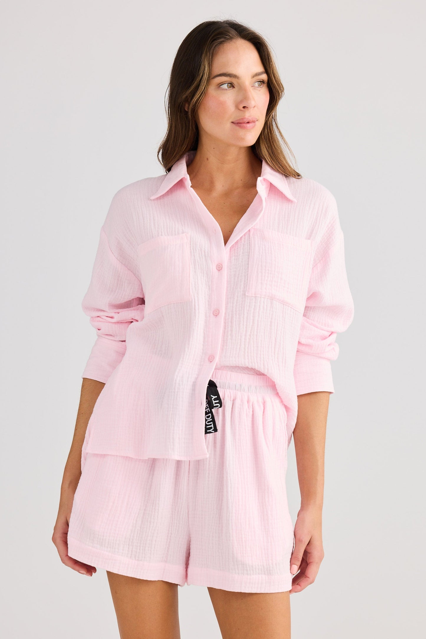 Woman wearing a pink shirt and shorts set on a white background