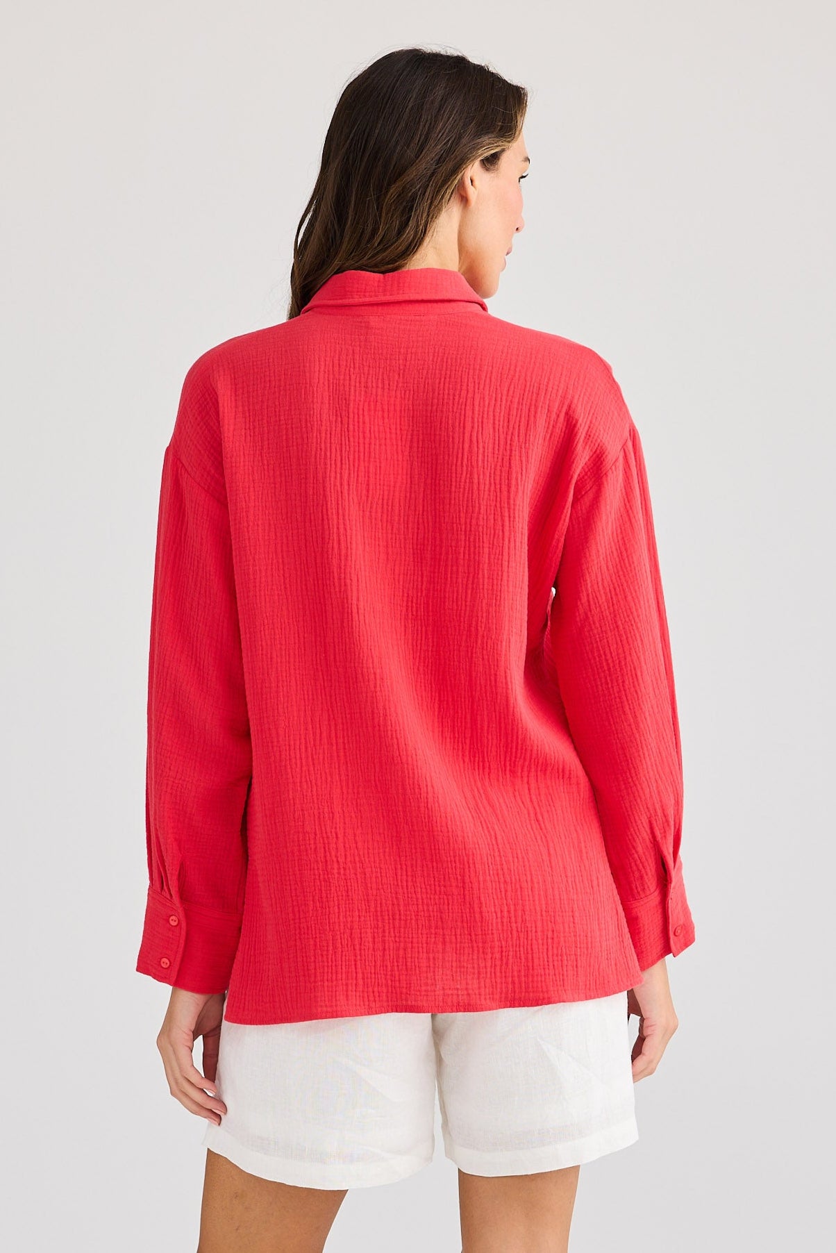 Person wearing a red shirt and white shorts on a light gray background