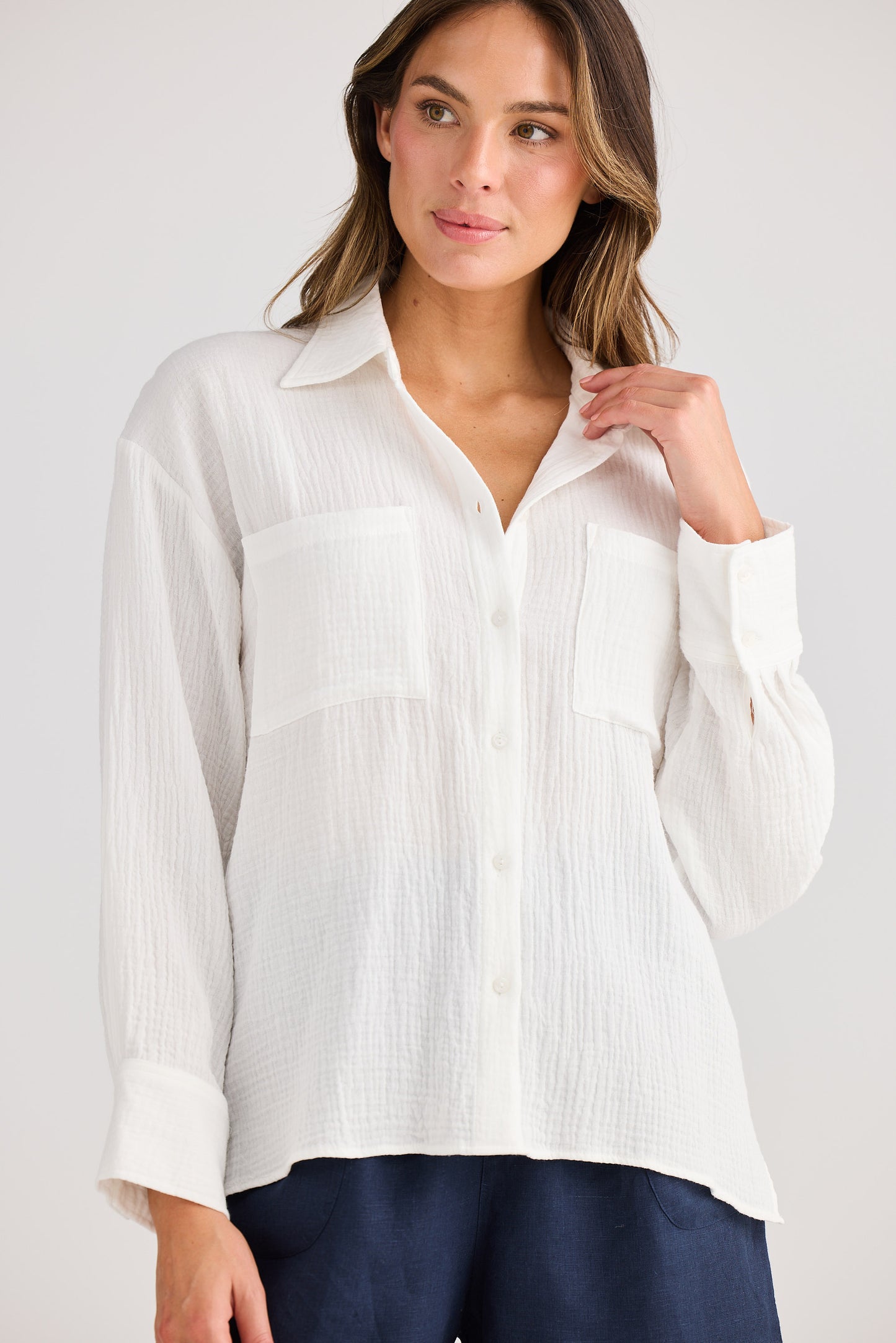 Woman wearing a white button-up shirt against a plain background