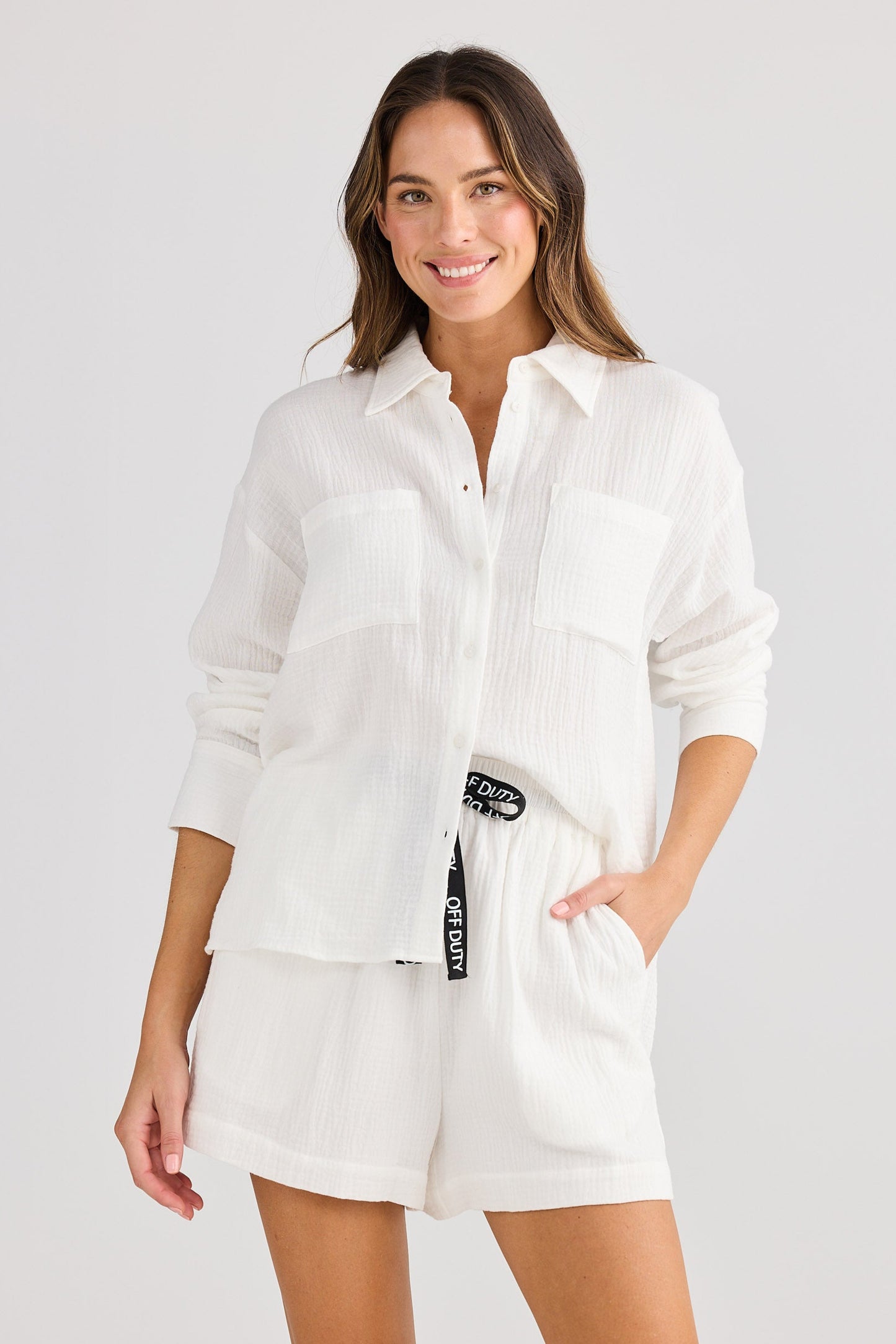 Woman wearing a white shirt and shorts on a plain background