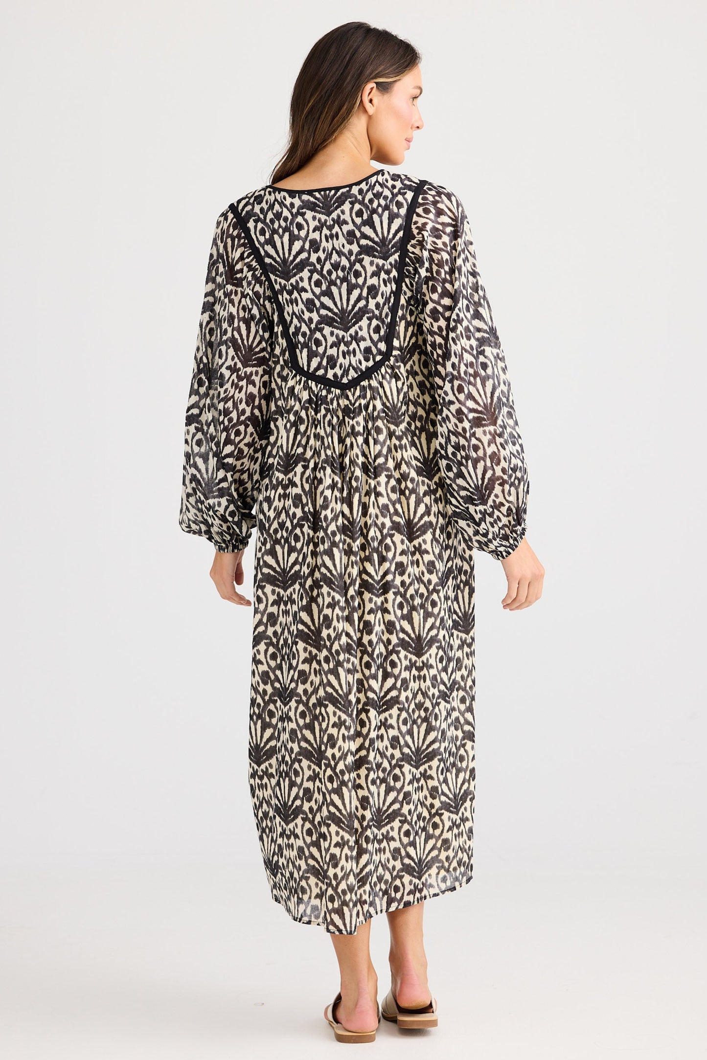 Woman wearing a long, patterned dress on a white background