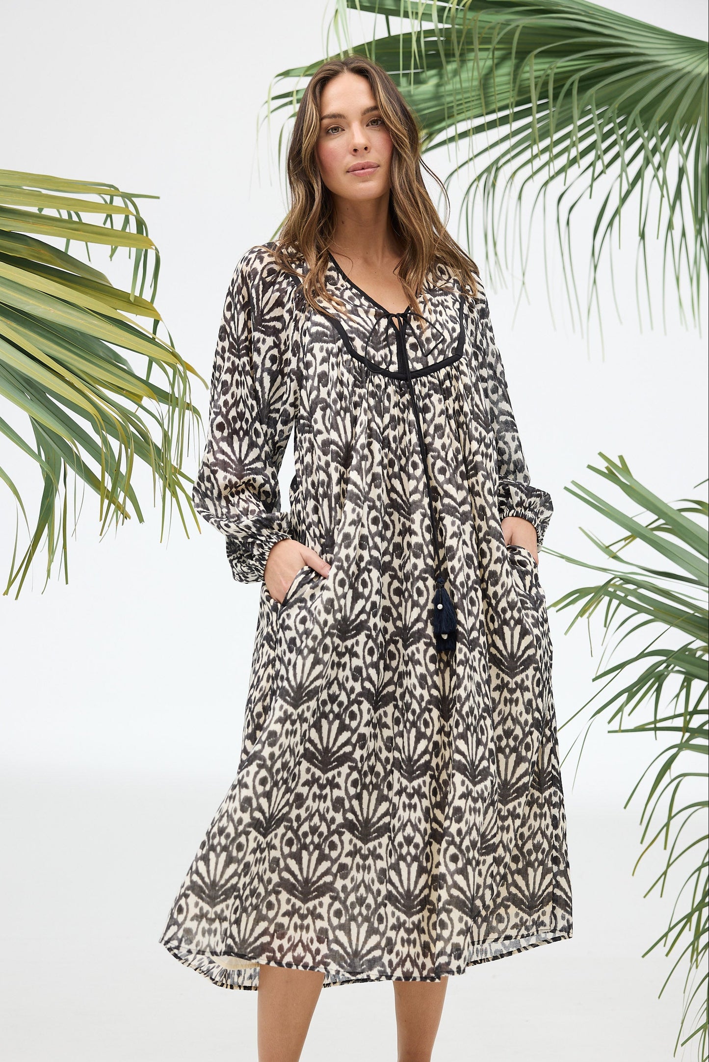 Woman wearing a patterned dress with palm leaves in the background