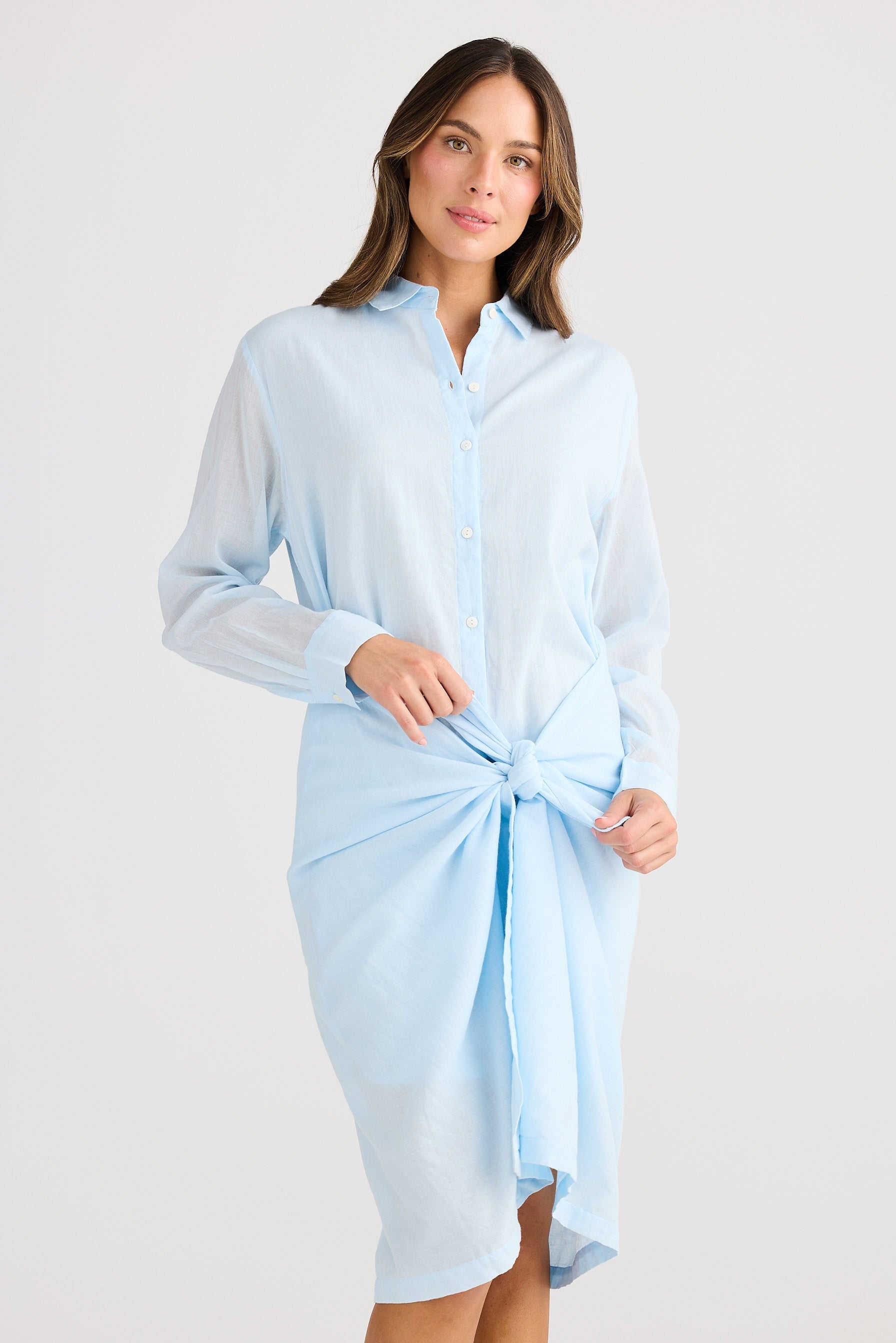 Woman wearing a light blue shirt dress on a white background