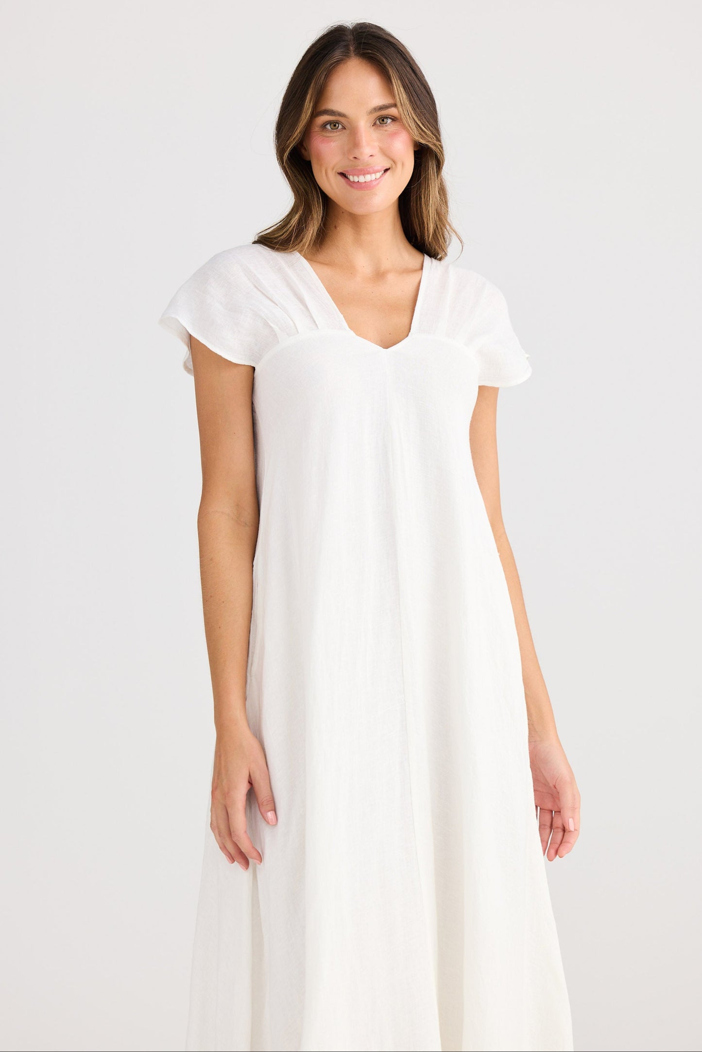 Woman wearing a white dress against a plain background