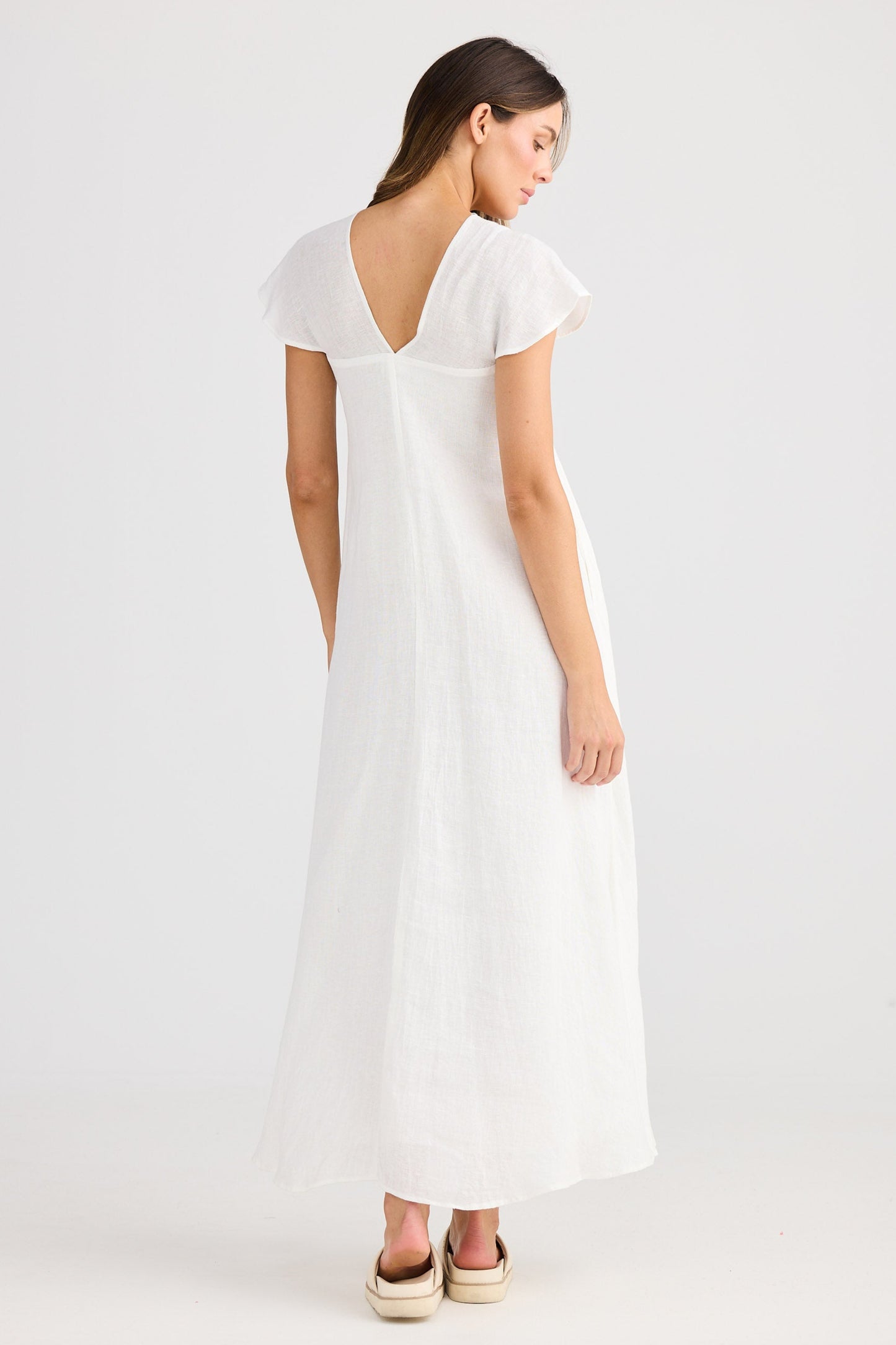 Woman wearing a white dress on a plain background