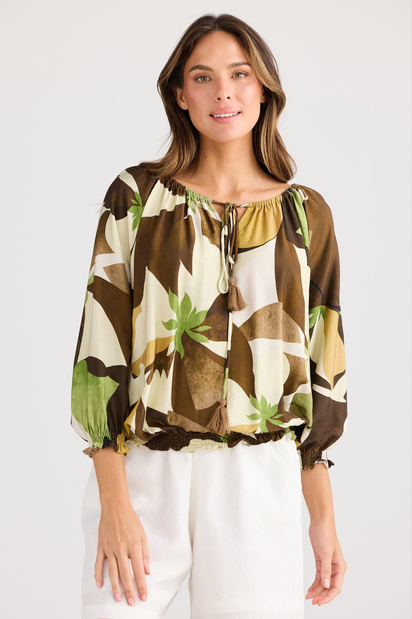 Woman wearing a patterned blouse and white shorts on a plain background