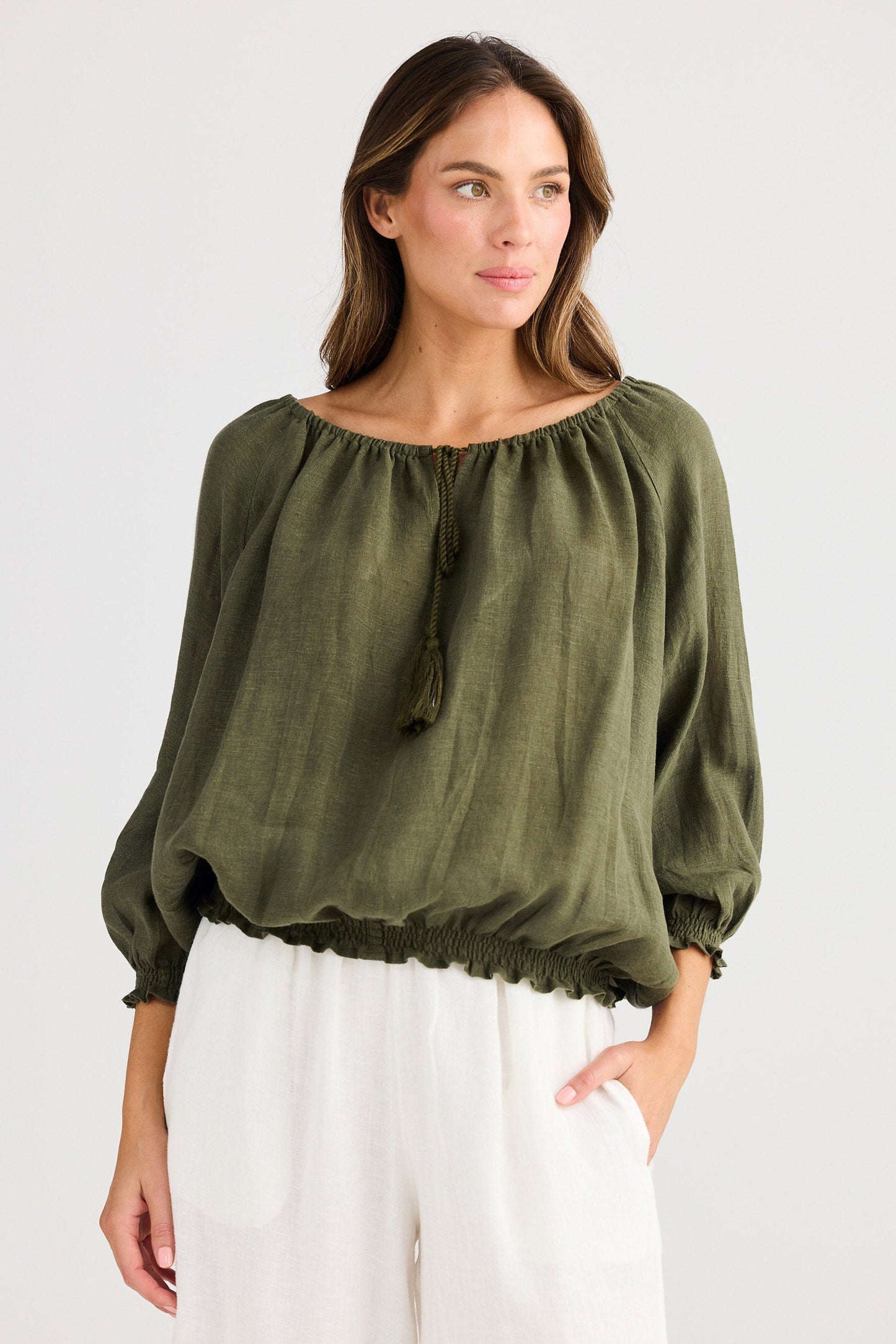 Woman wearing an olive green blouse with balloon sleeves on a white background