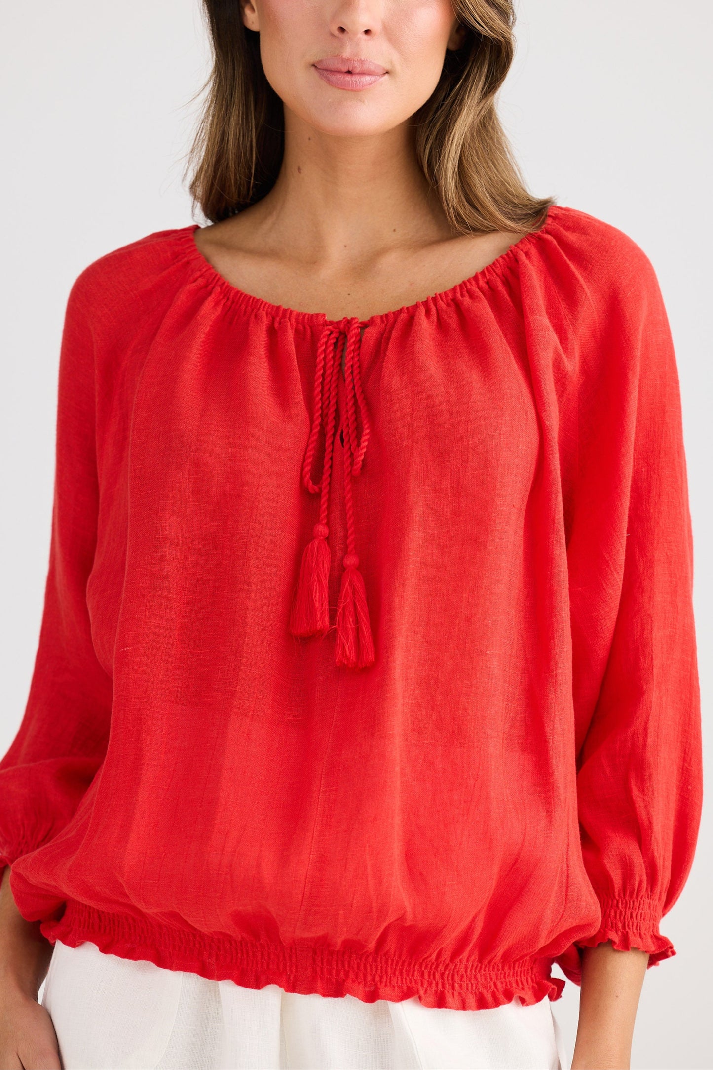 Woman wearing a red blouse with long sleeves on a white background