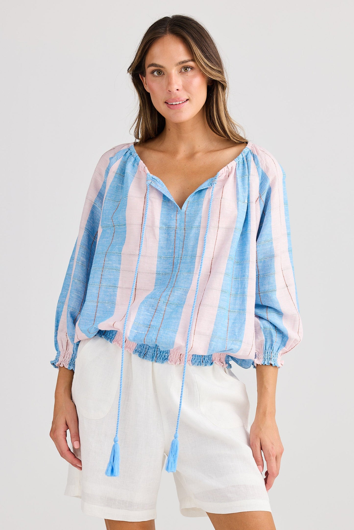 Woman wearing a striped top and white shorts on a plain background