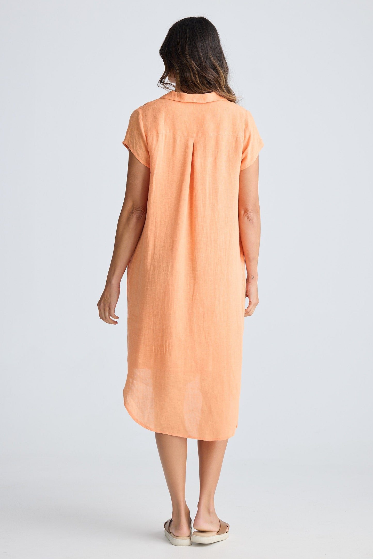 Woman wearing a peach-colored dress on a white background