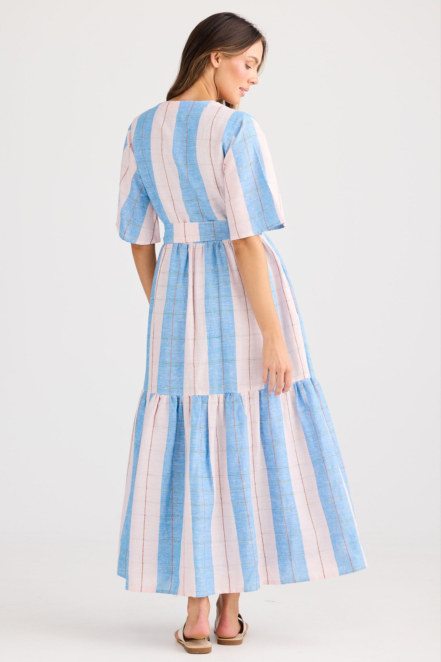 Woman wearing a blue and white striped dress on a light gray background