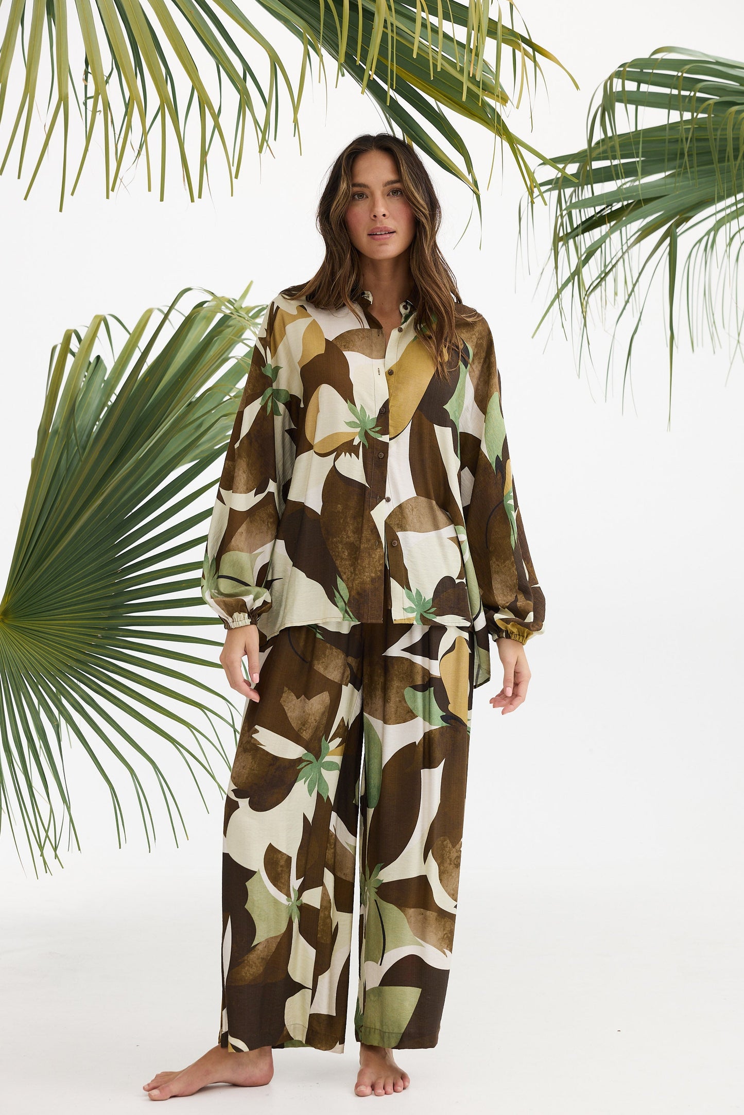 Woman wearing a patterned outfit with palm leaves in the background