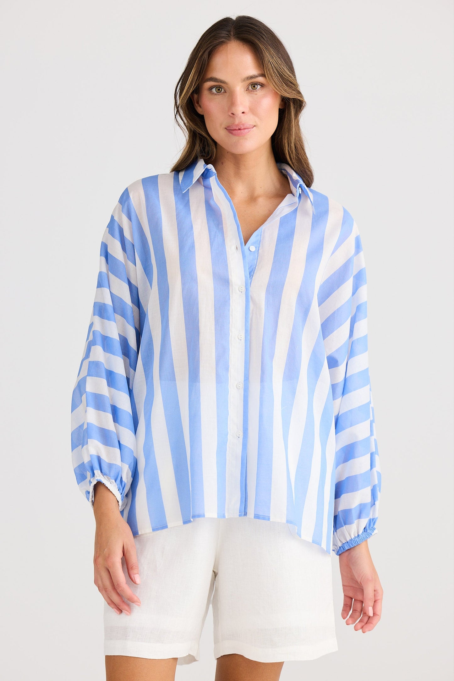 Woman wearing a blue and white striped shirt on a plain background