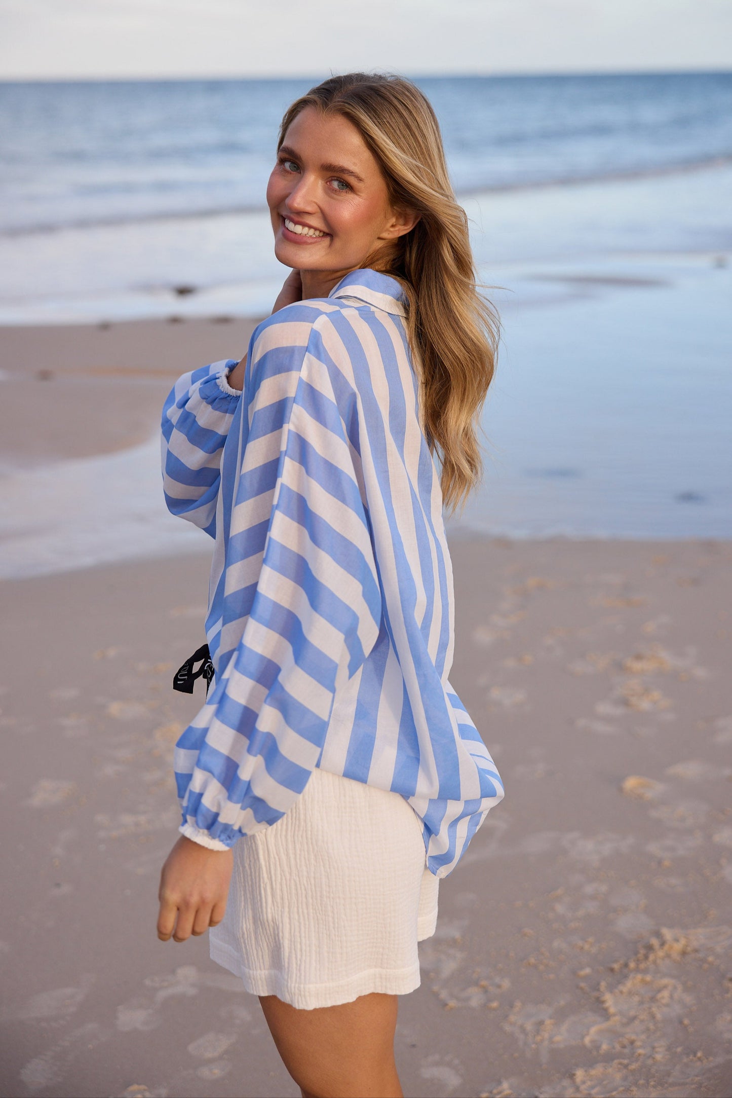 Woman wearing a blue and white striped shirt on a beach