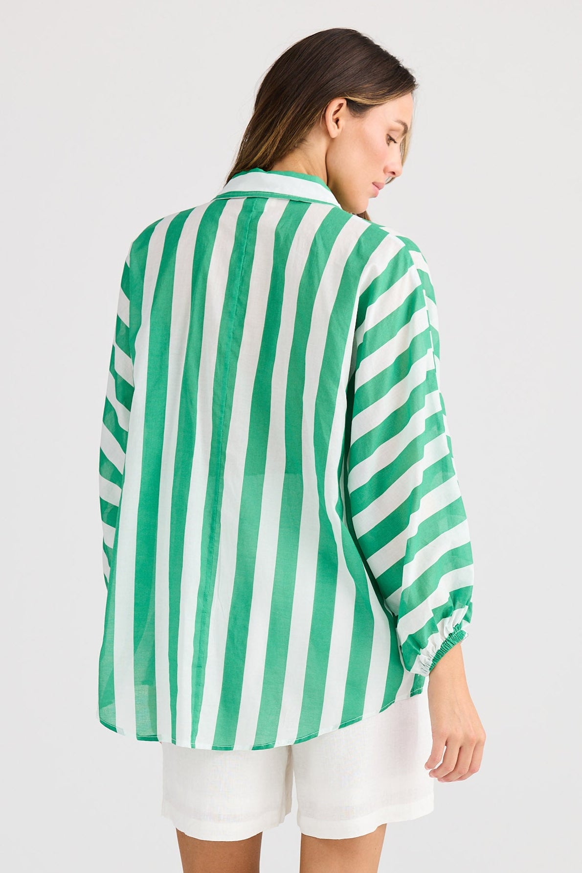 Woman wearing a green and white striped shirt on a plain background