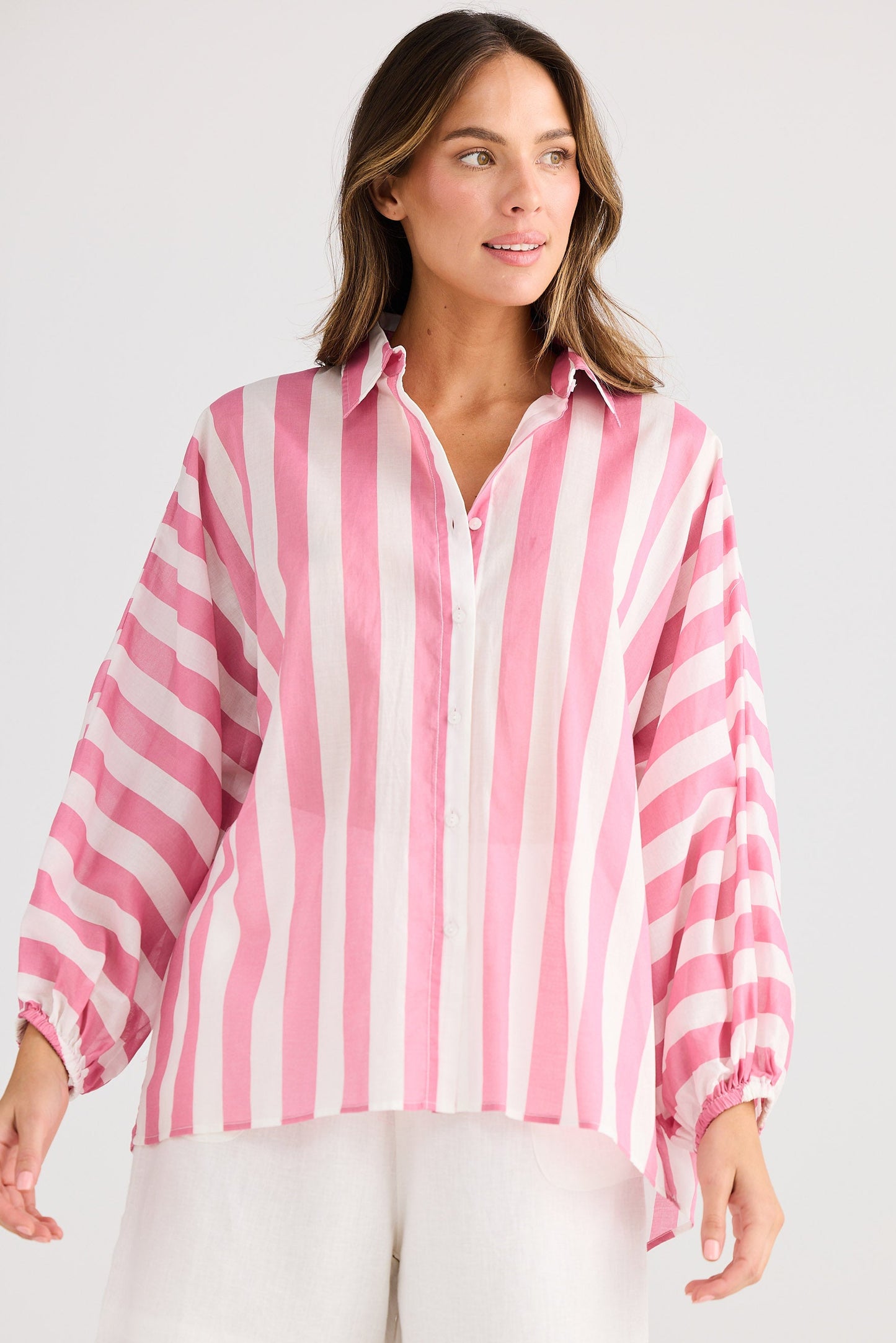 Woman wearing a pink and white striped shirt with a plain background