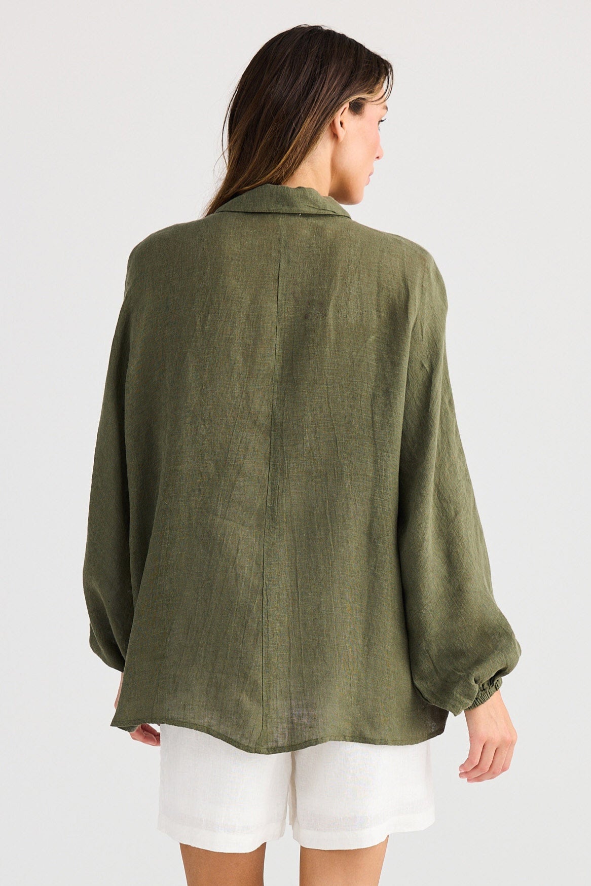 Woman wearing an olive green shirt and white shorts on a white background
