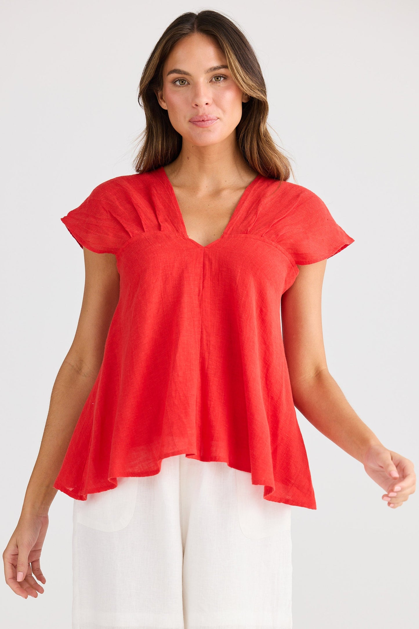 Woman wearing a red top and white shorts on a plain background