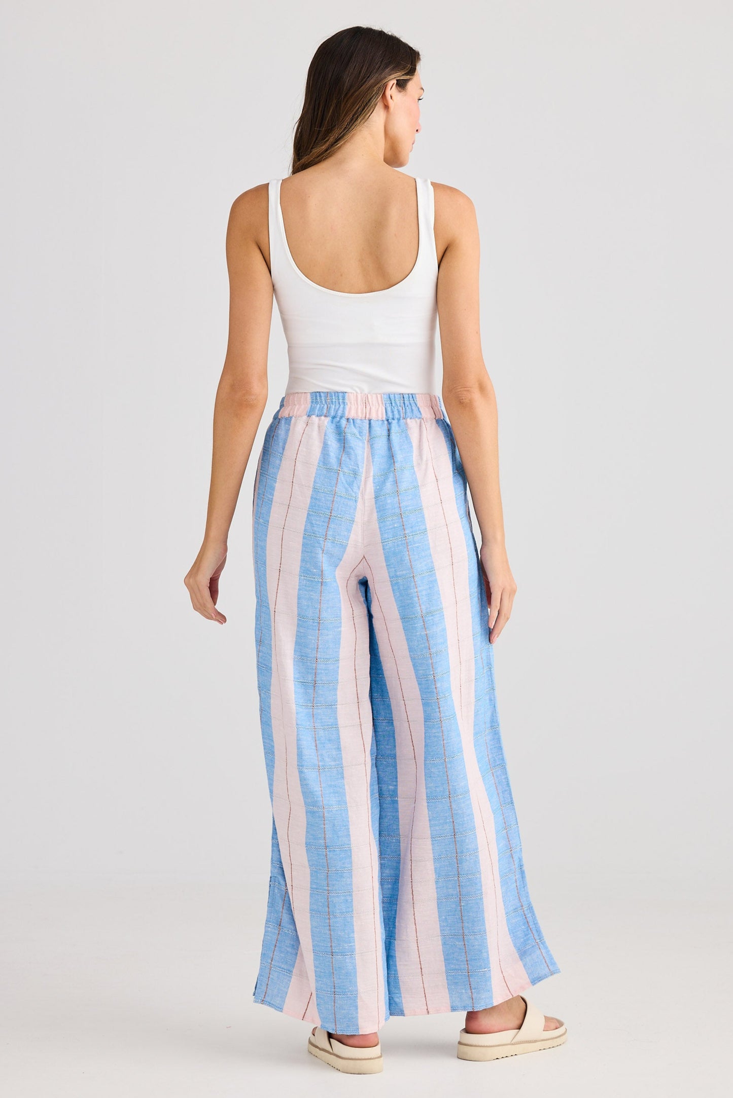 Woman wearing a white top and blue and pink striped pants on a white background