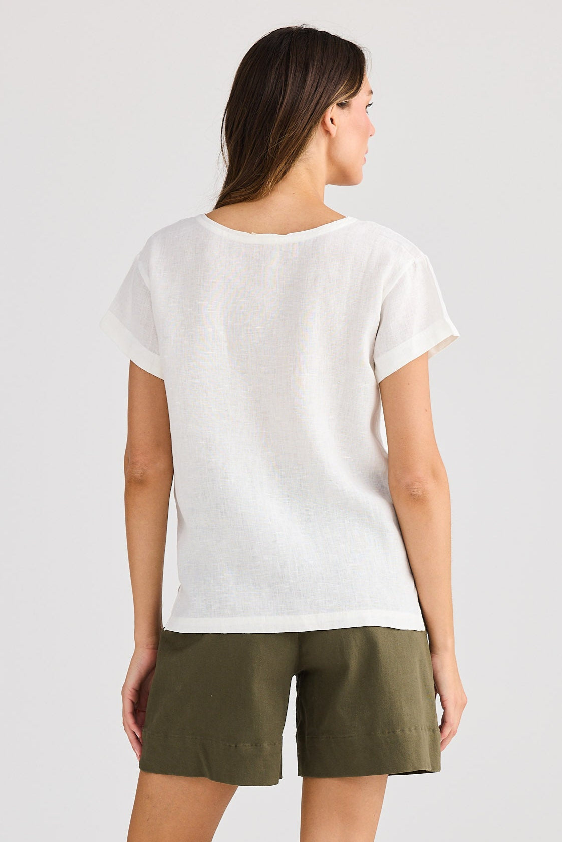 Woman wearing a white t-shirt and green shorts on a plain background