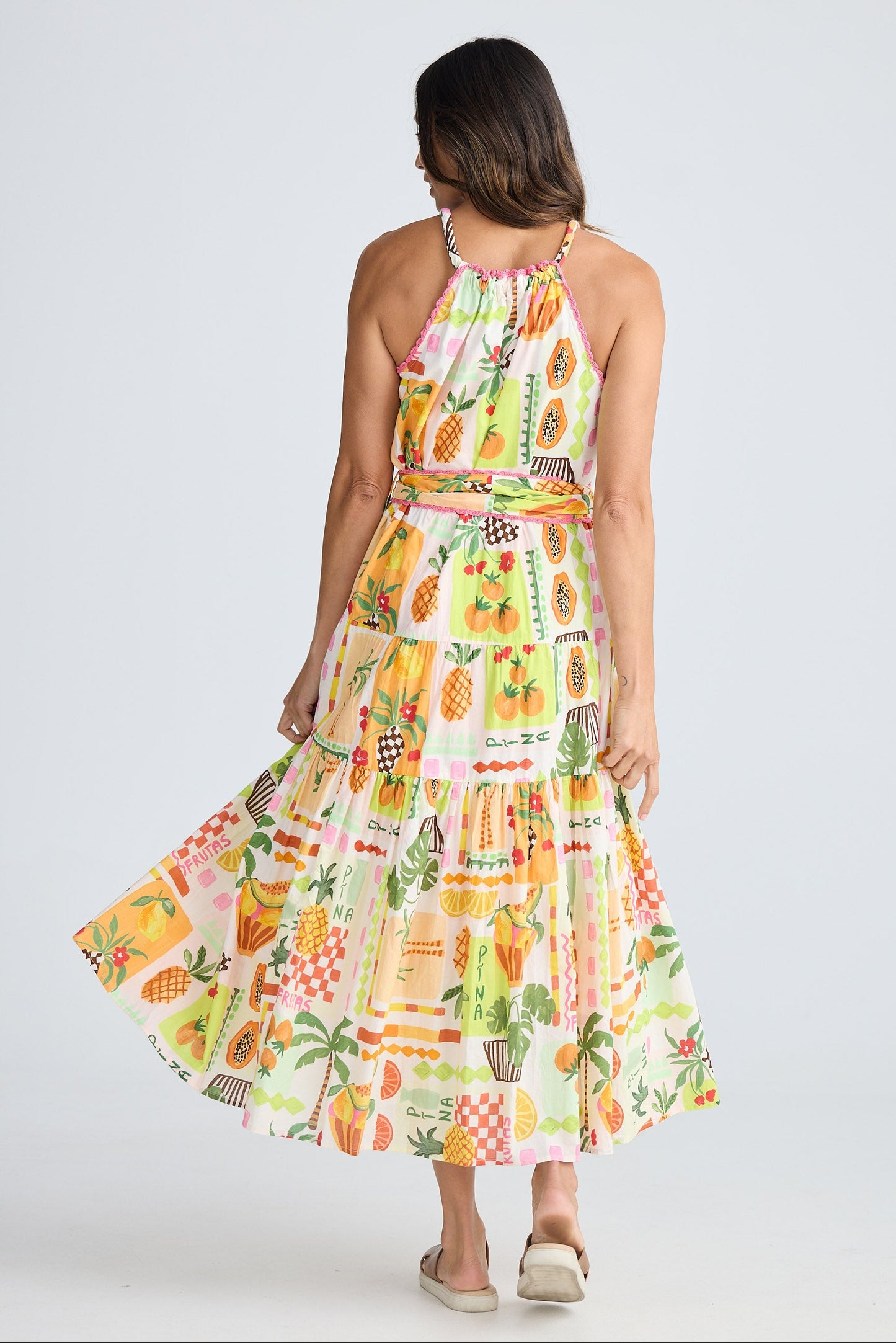 Woman wearing a colorful pineapple patterned dress on a white background