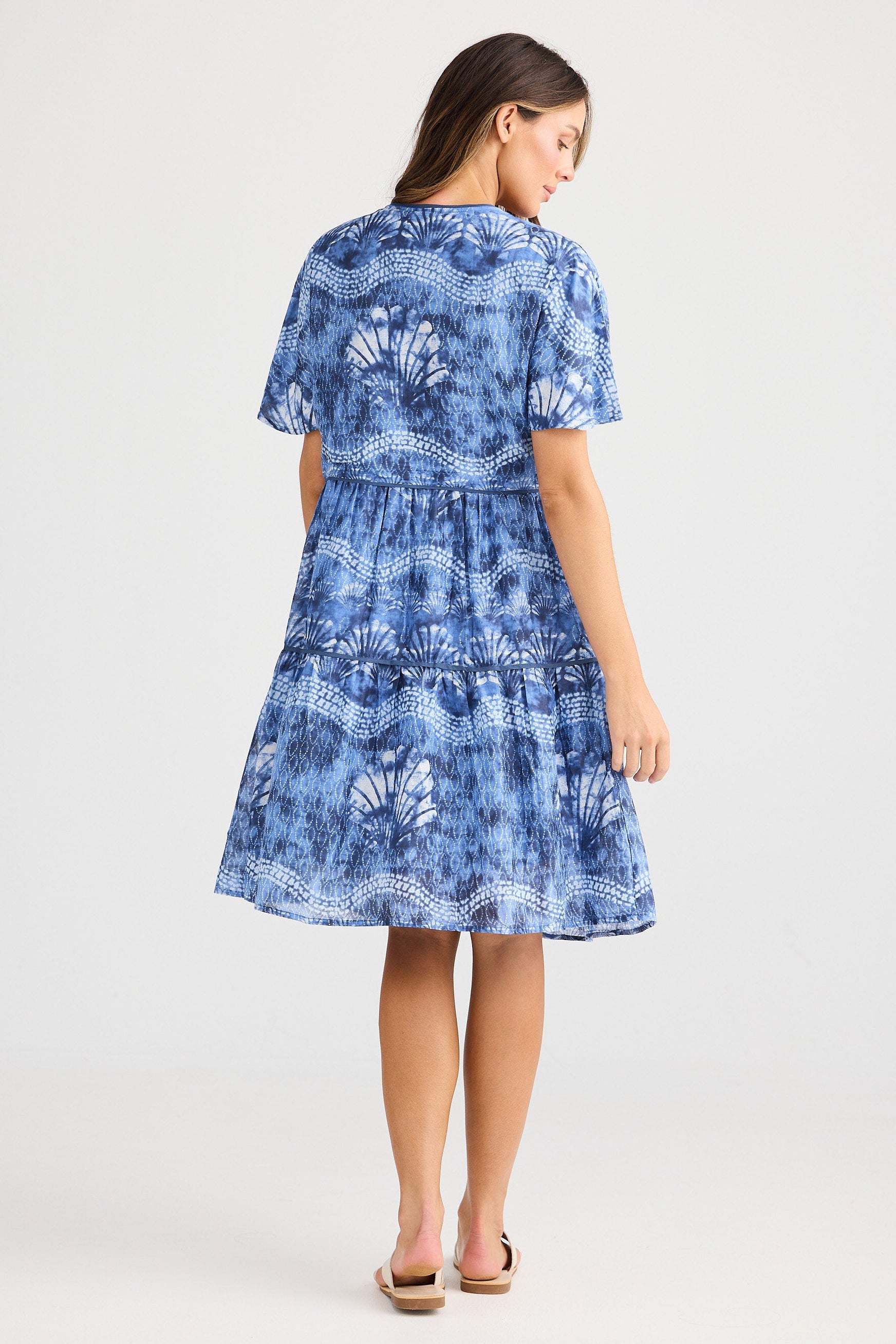 Woman wearing a blue patterned dress on a white background