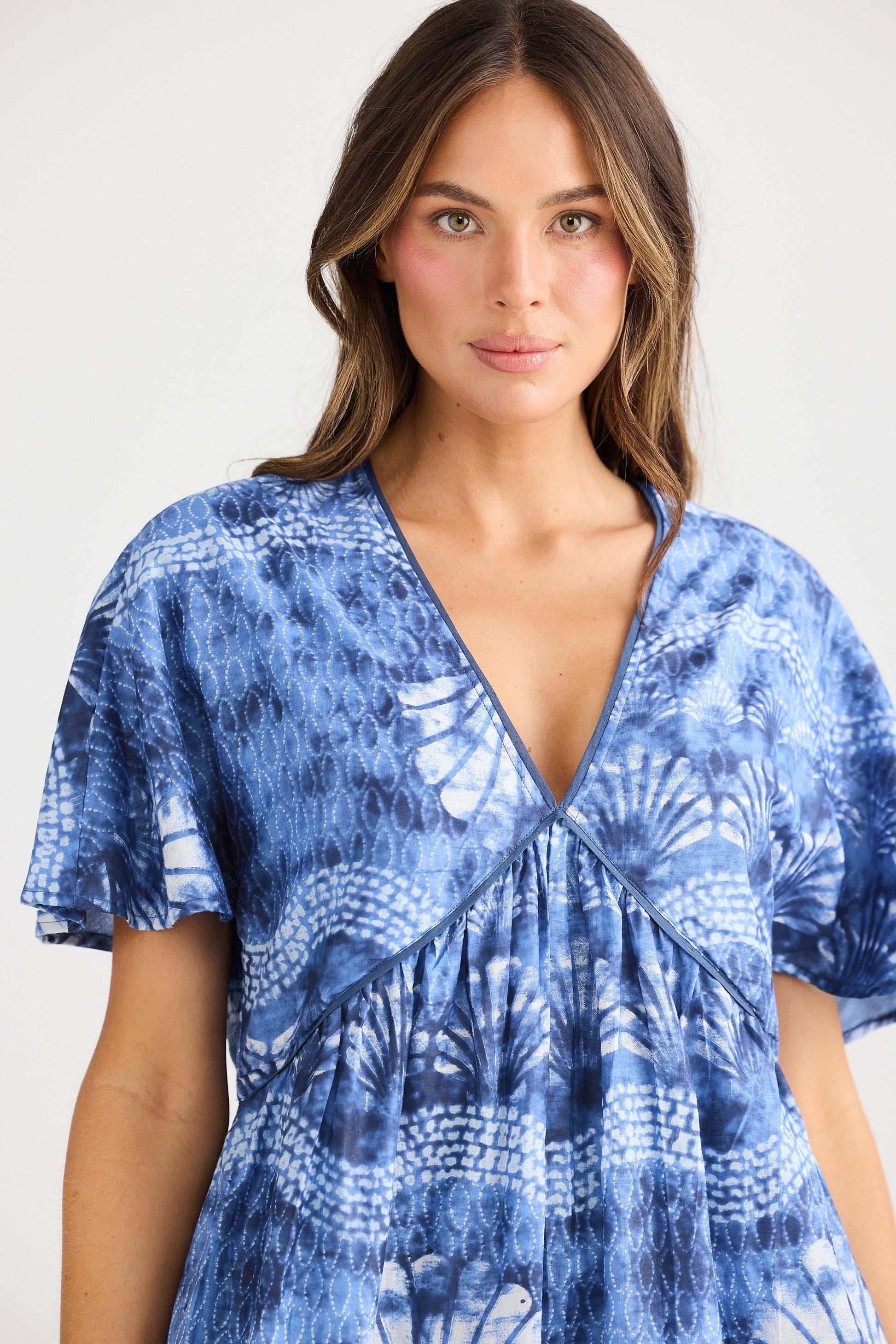 Woman wearing a blue patterned dress against a white background