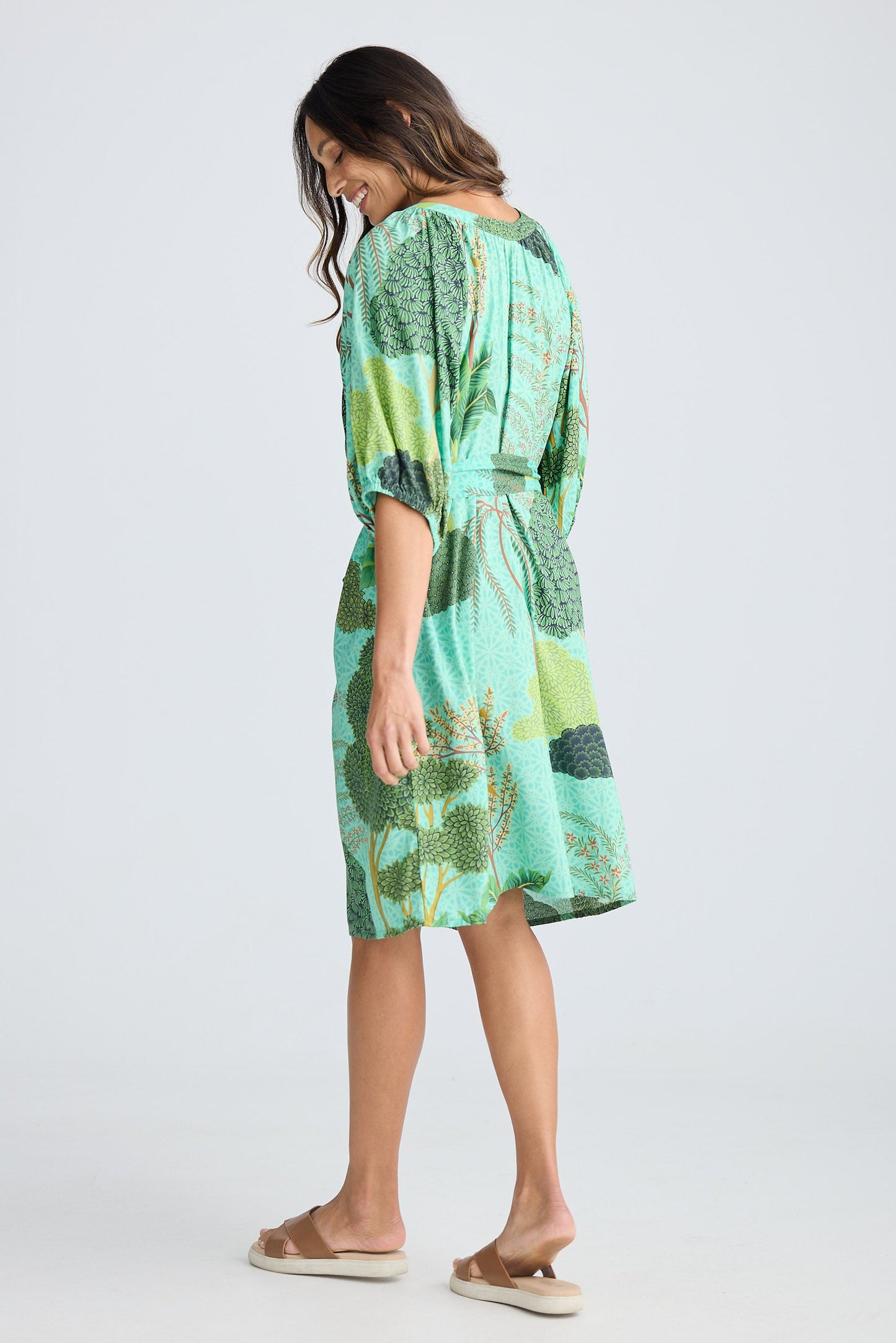 Woman wearing a green patterned dress on a white background