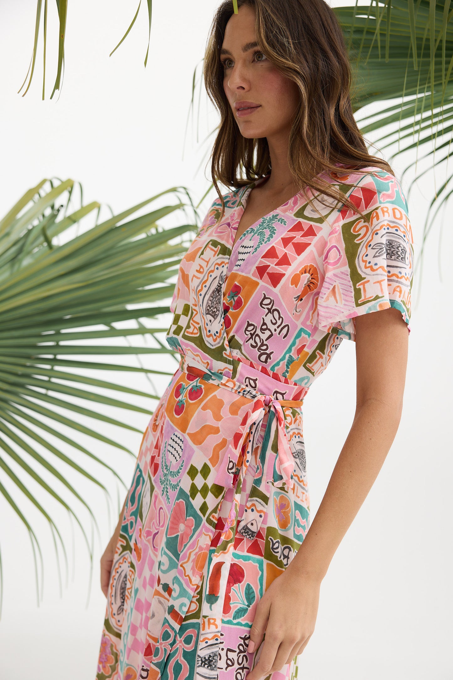Woman wearing a colorful patterned dress with palm leaves in the background