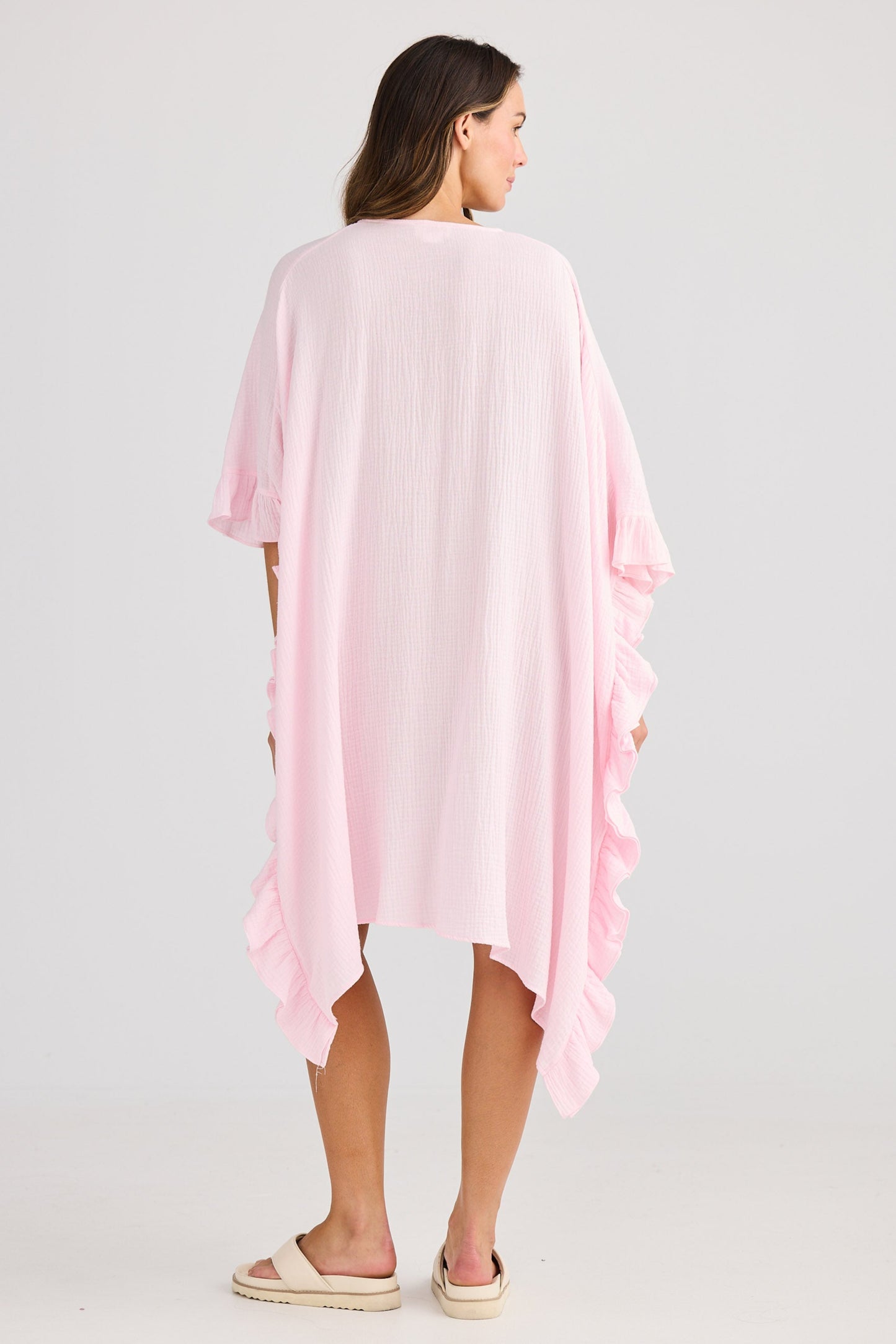 Woman wearing a light pink kimono-style garment on a white background