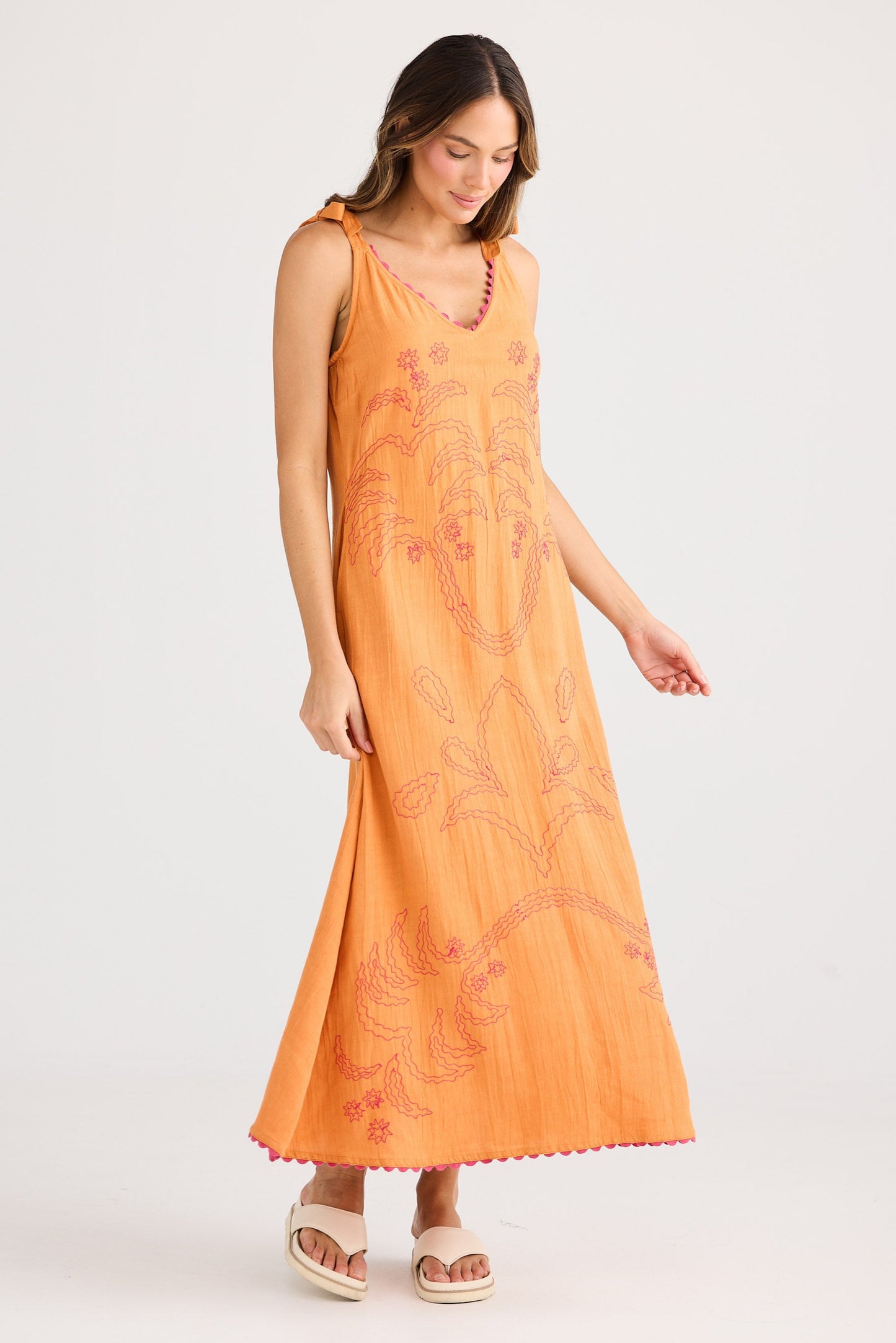 Woman wearing an orange dress with floral patterns on a white background