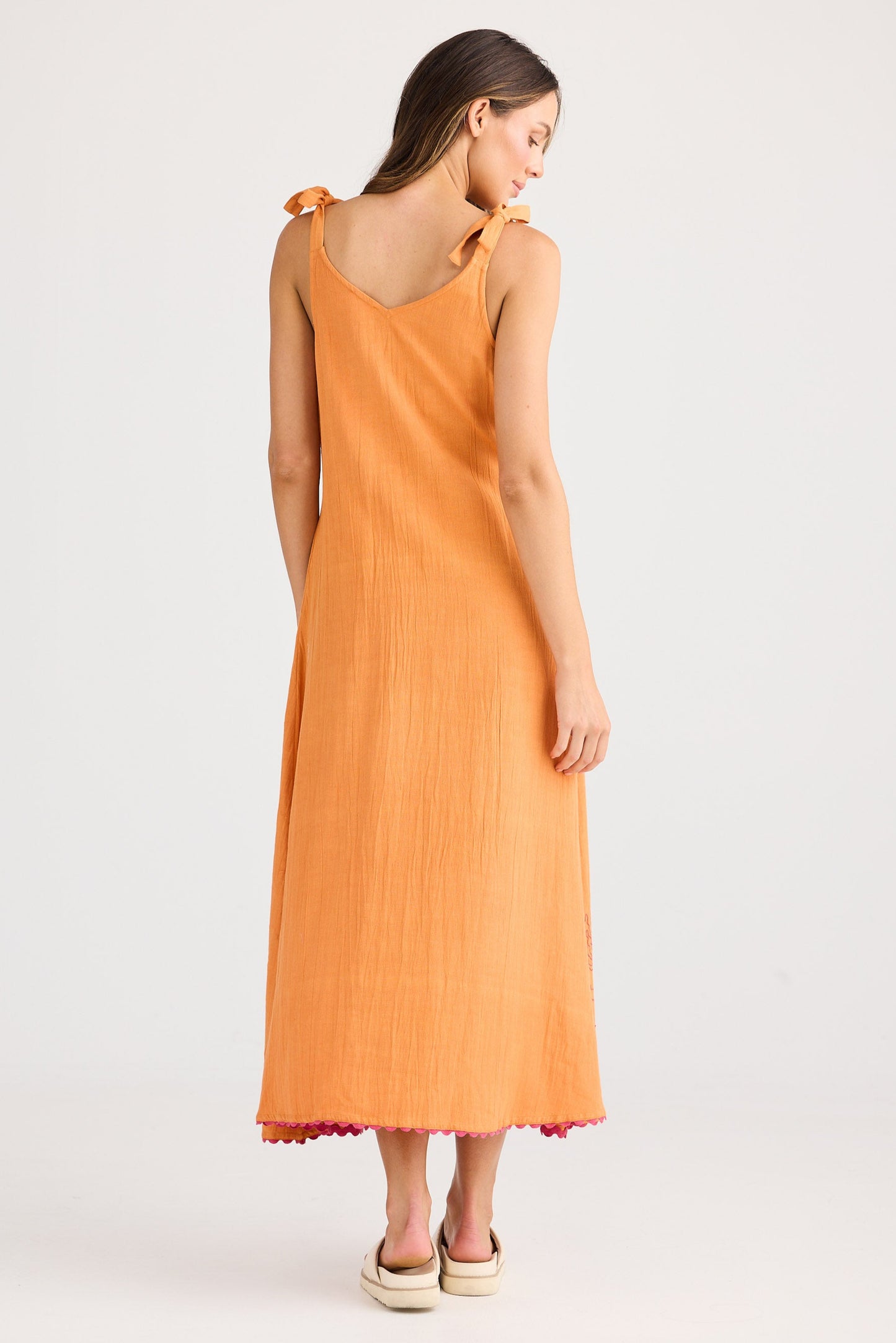 Woman wearing a long orange dress on a white background