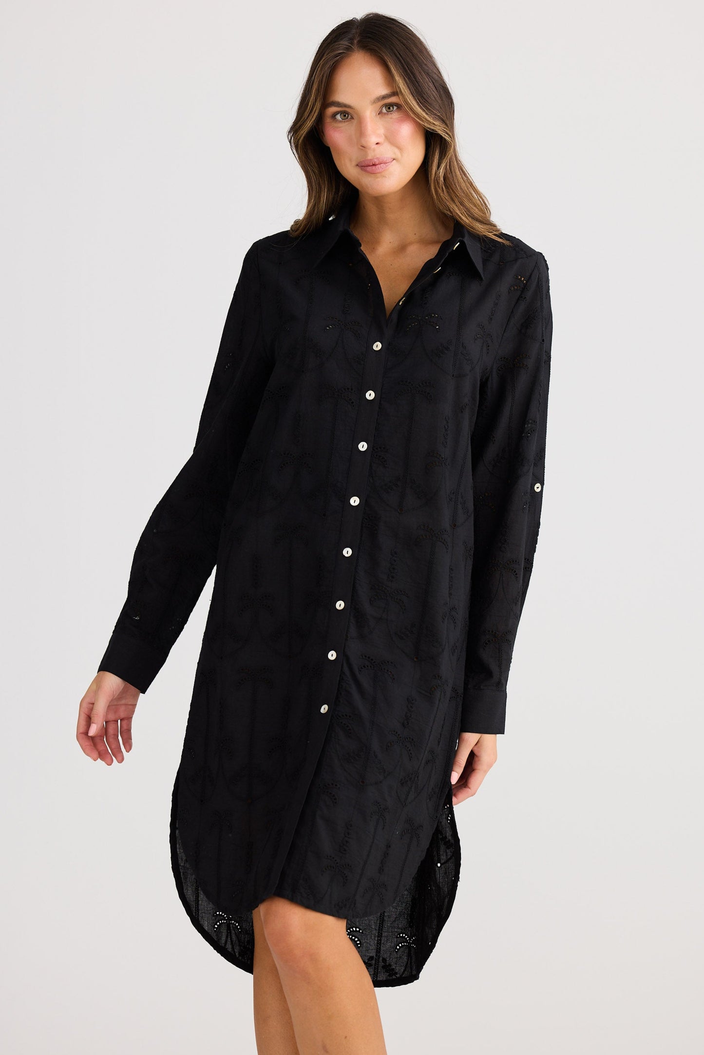 Woman wearing a black button-up shirt dress on a white background