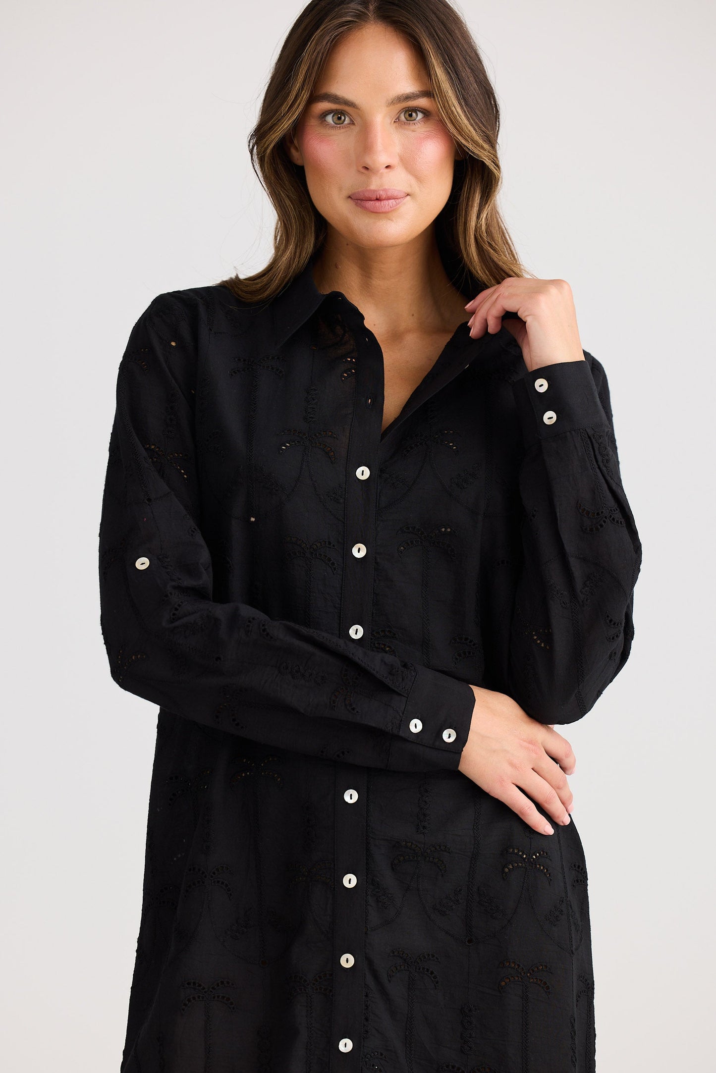 Woman wearing a black button-up dress against a white background